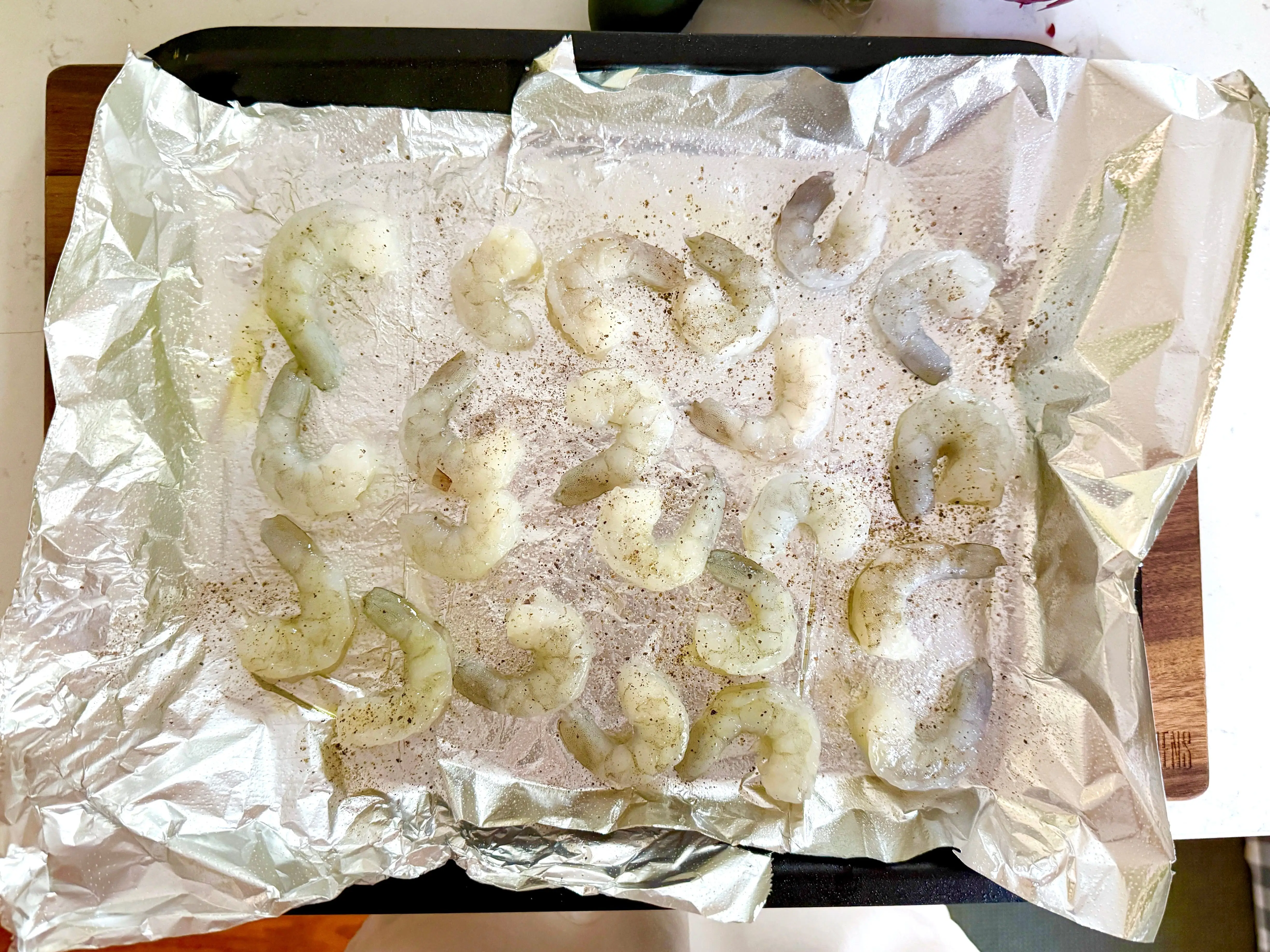 Shrimp spread out on a pan with foil.