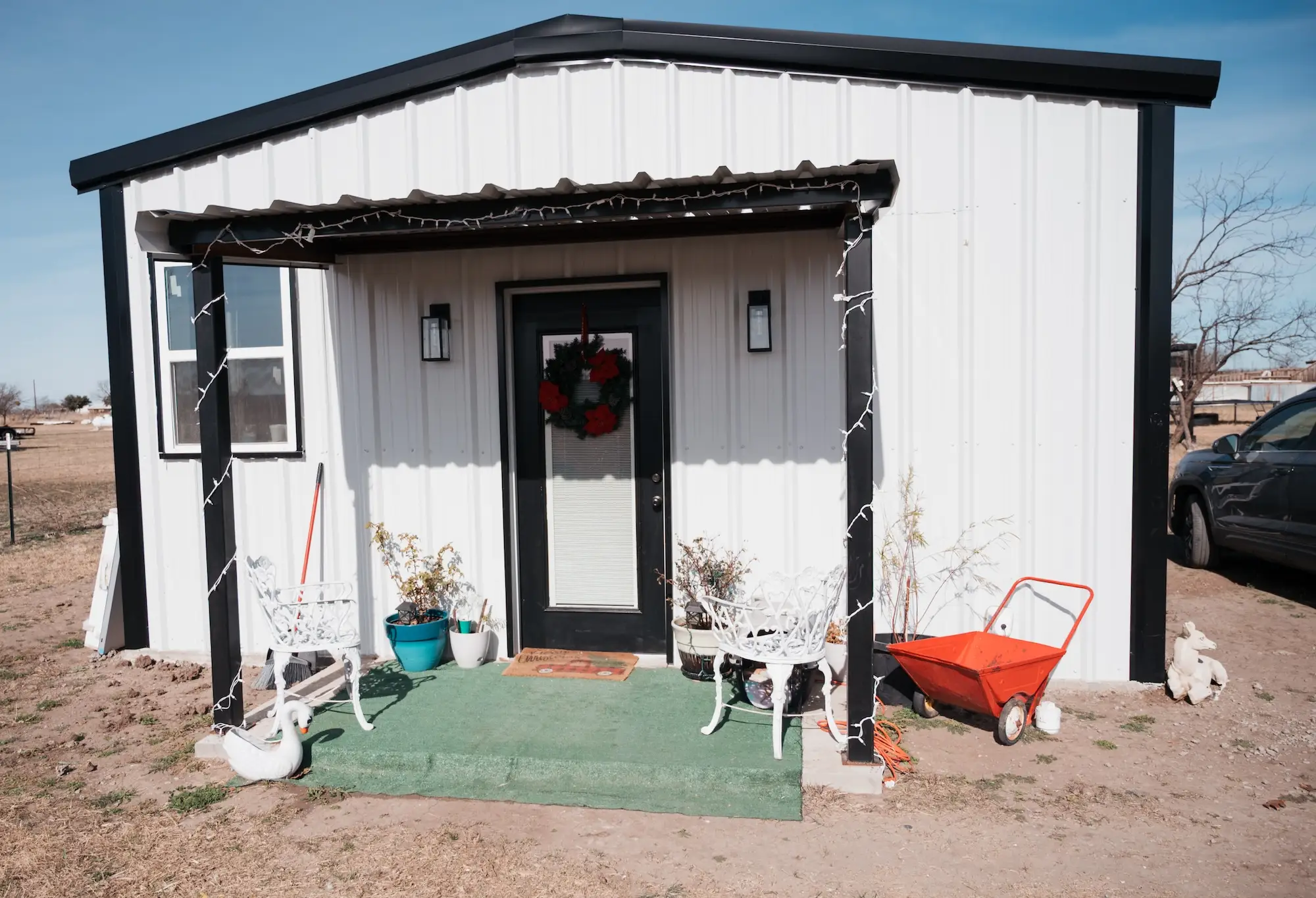 A white tiny home with a wreath on the front door.