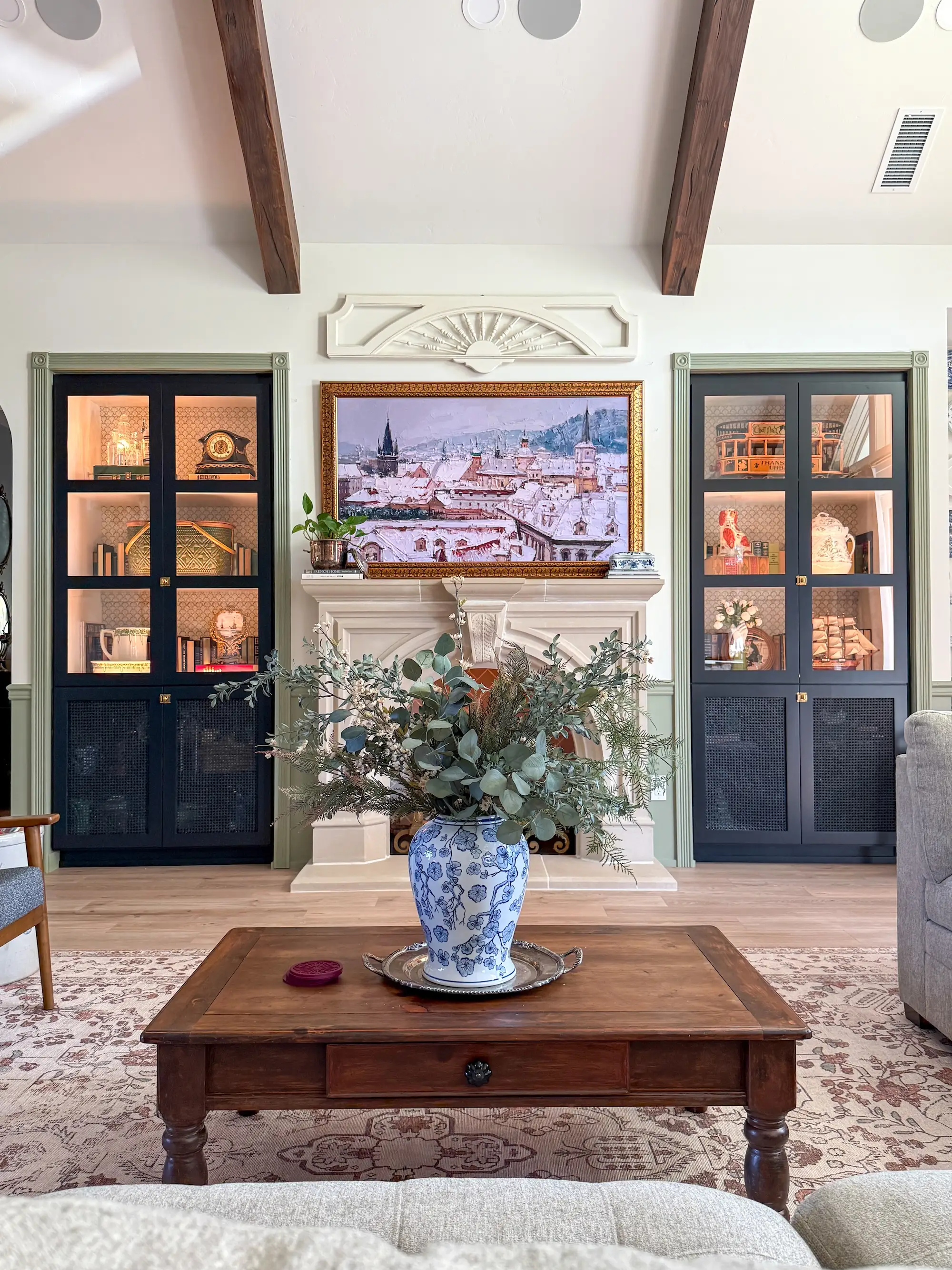 A living room with a frame tv and fireplace framed by built-in bookshelves.