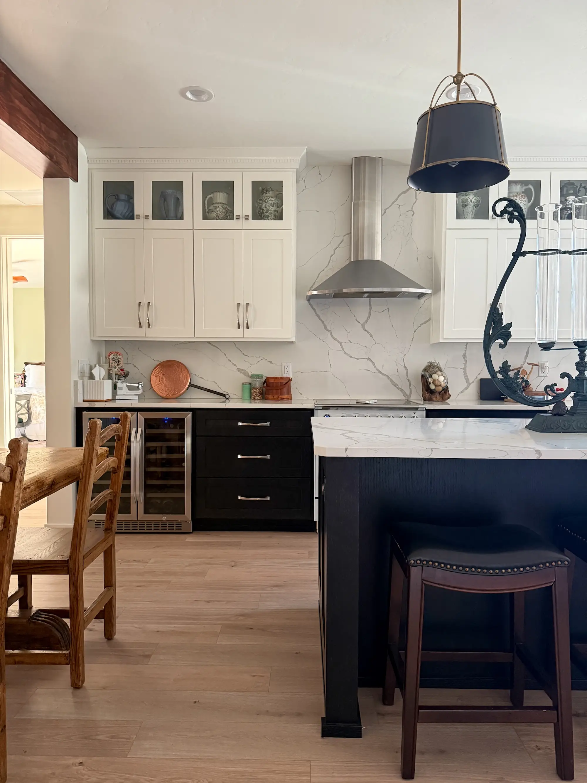 A kitchen with black and white cabinetry and a wine fridge.