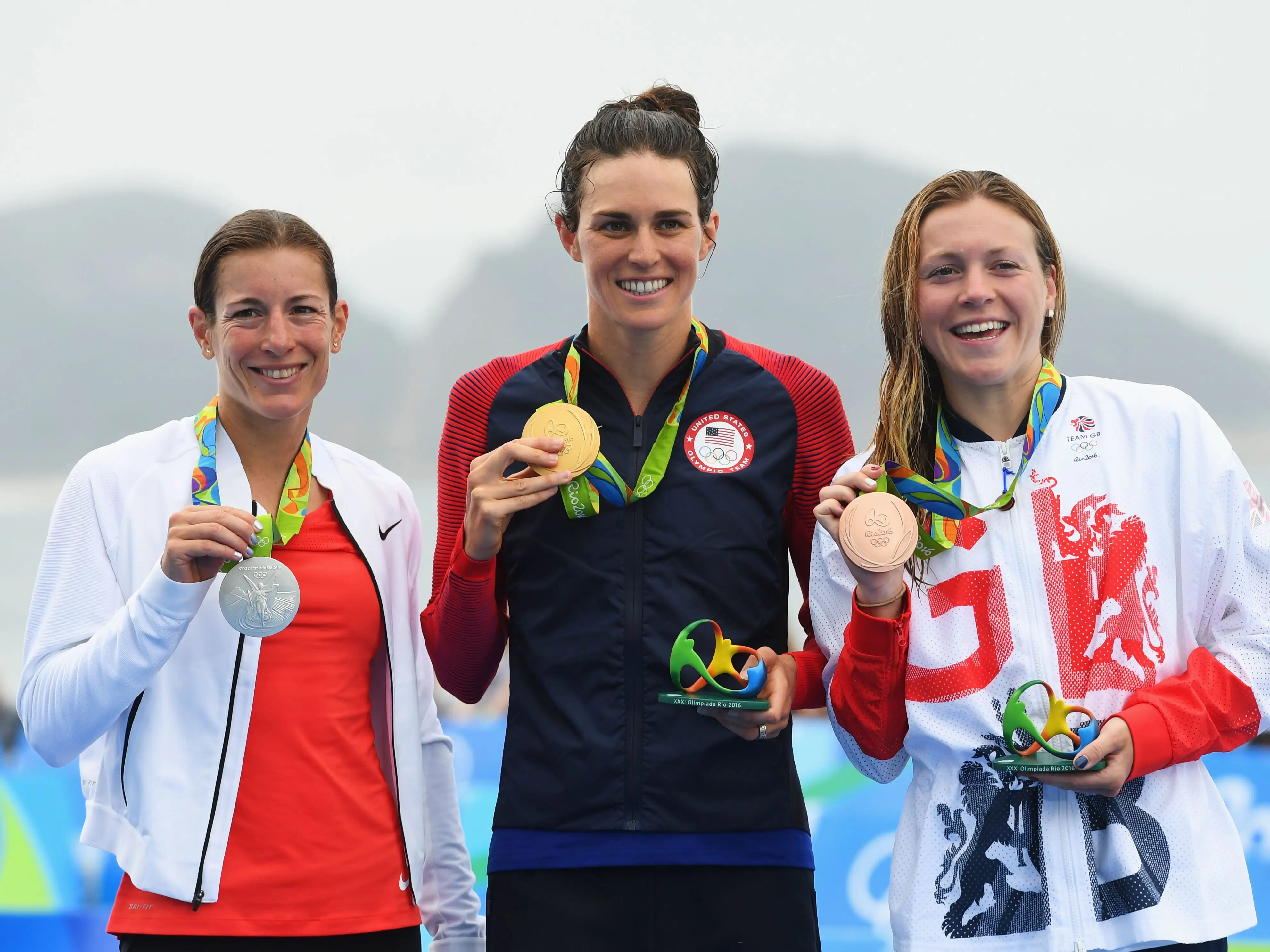 Silver medalist Nicola Spirig, gold medalist Gwen Jorgensen, and bronze medalist Vicky Holland celebrate on the podium after the 2016 Olympic triathlon.