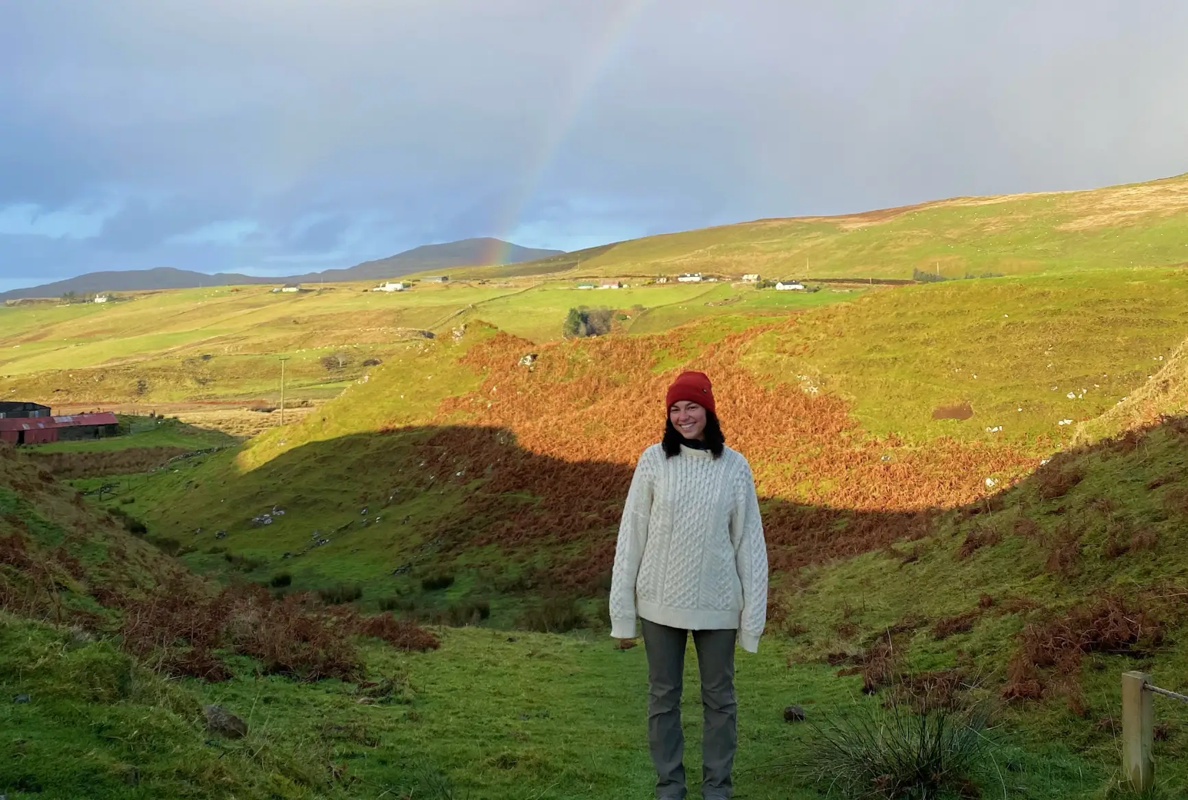 The writer standing in front of hills at Fairy Glen in Scotland.