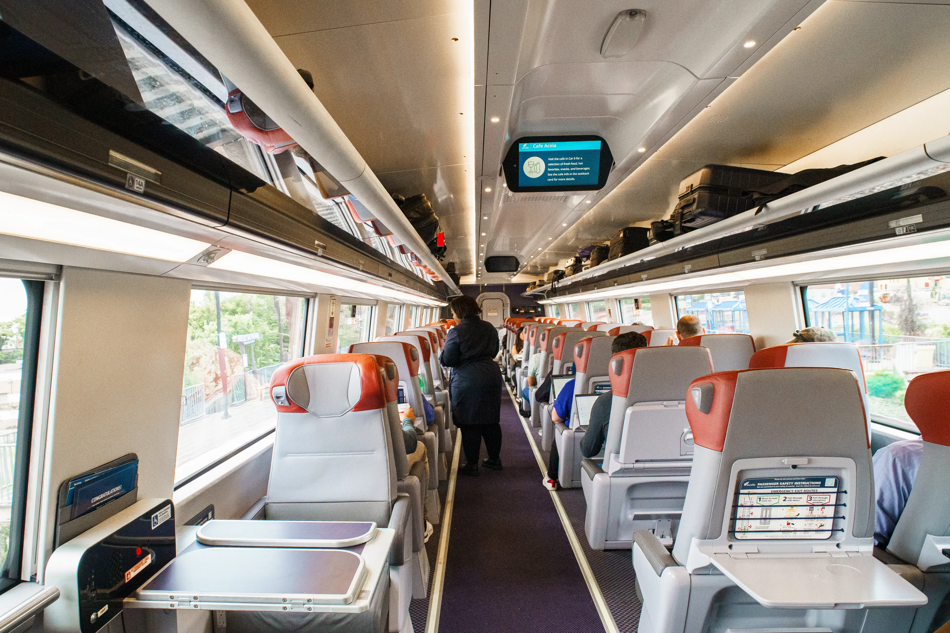 A wide view of a first-class Amtrak Acela car with a row of single seats on the left and a row of double seats on the right