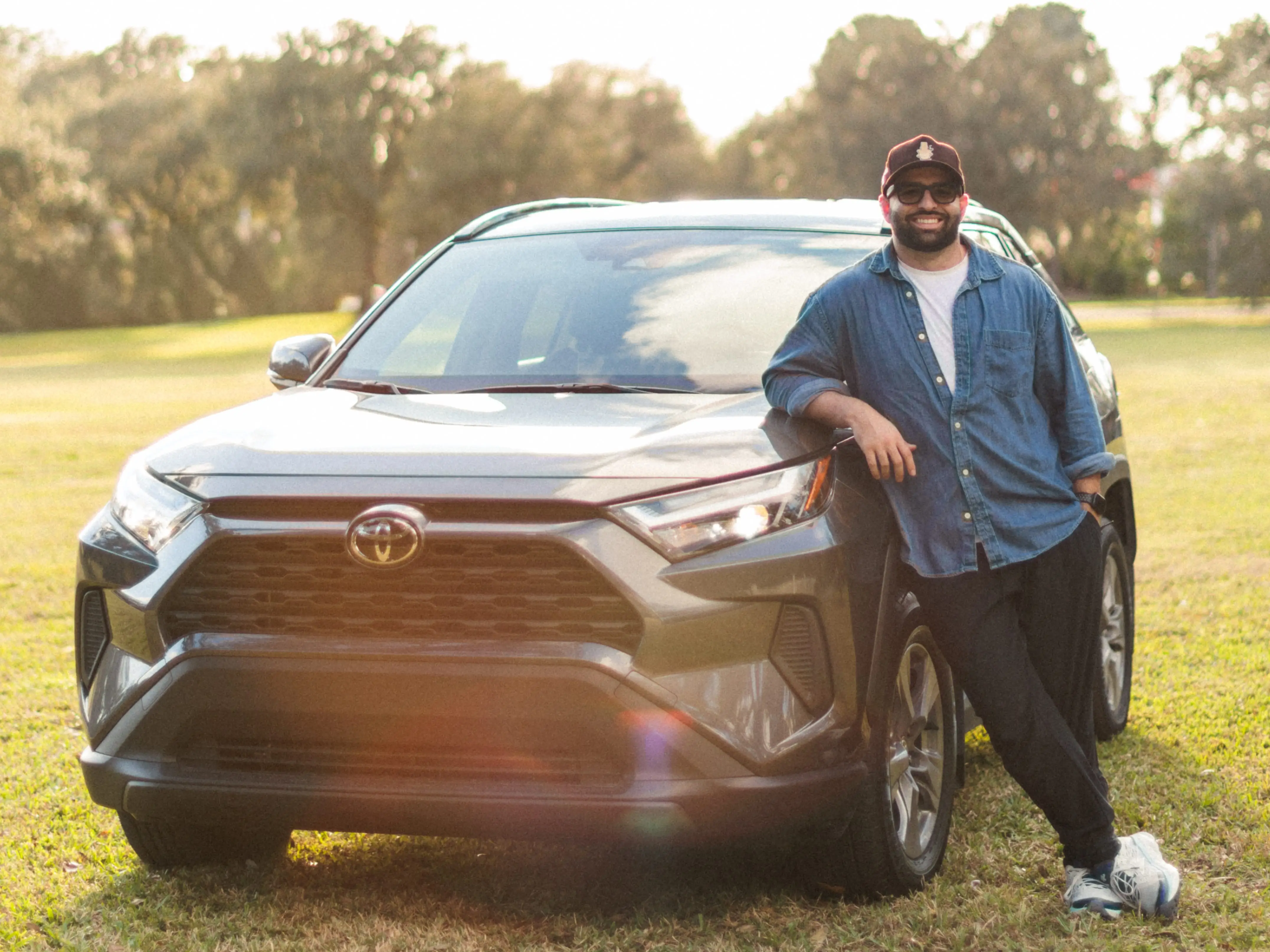 Author Vincent Rives leaning on Rav4 in grassy field