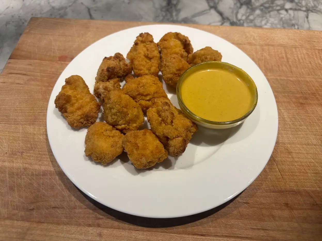 Chicken nuggets on plate with bowl of mustard