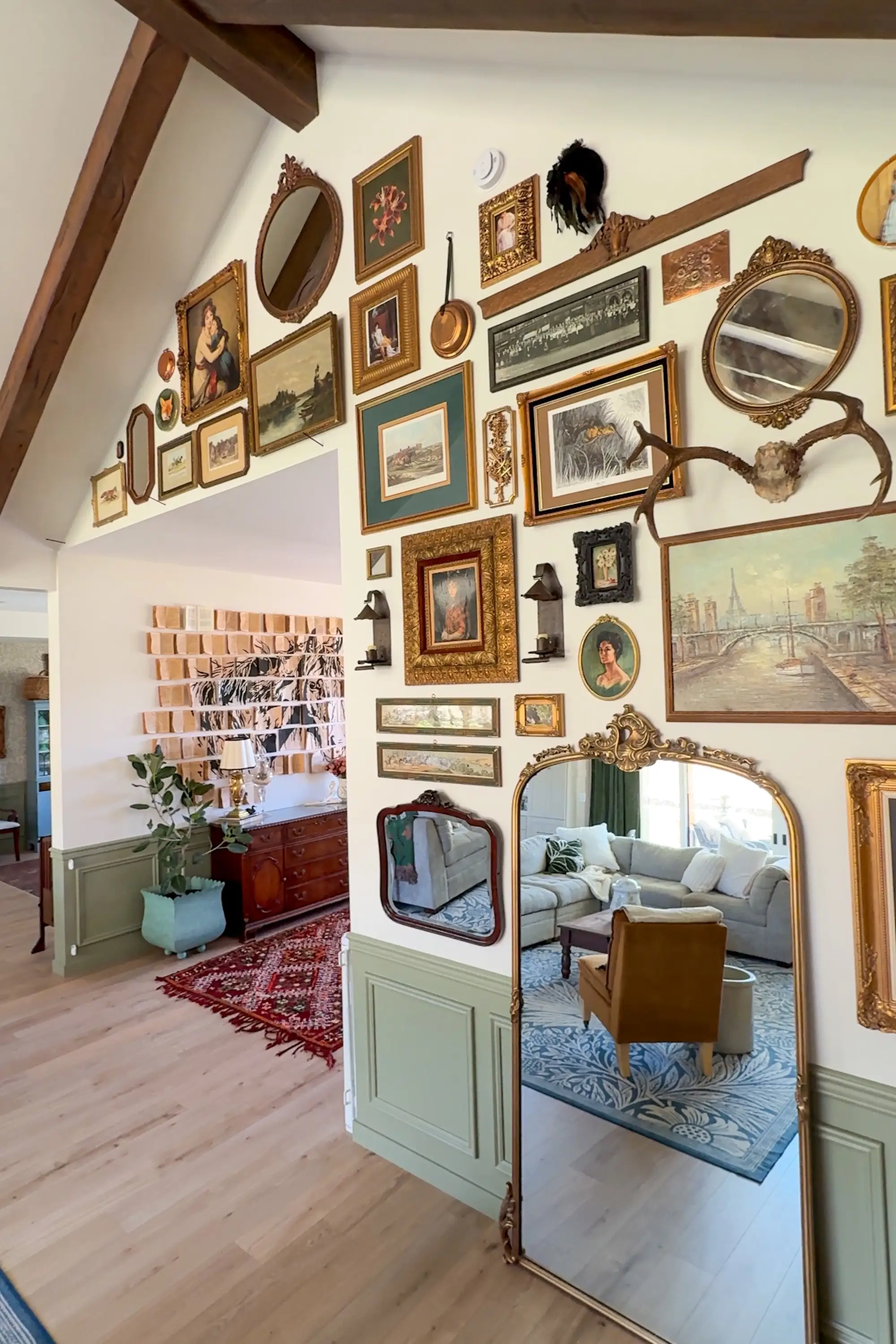 A wall covered in inricate paintings with a mirror. Another wall nearby is covered with books as decor.