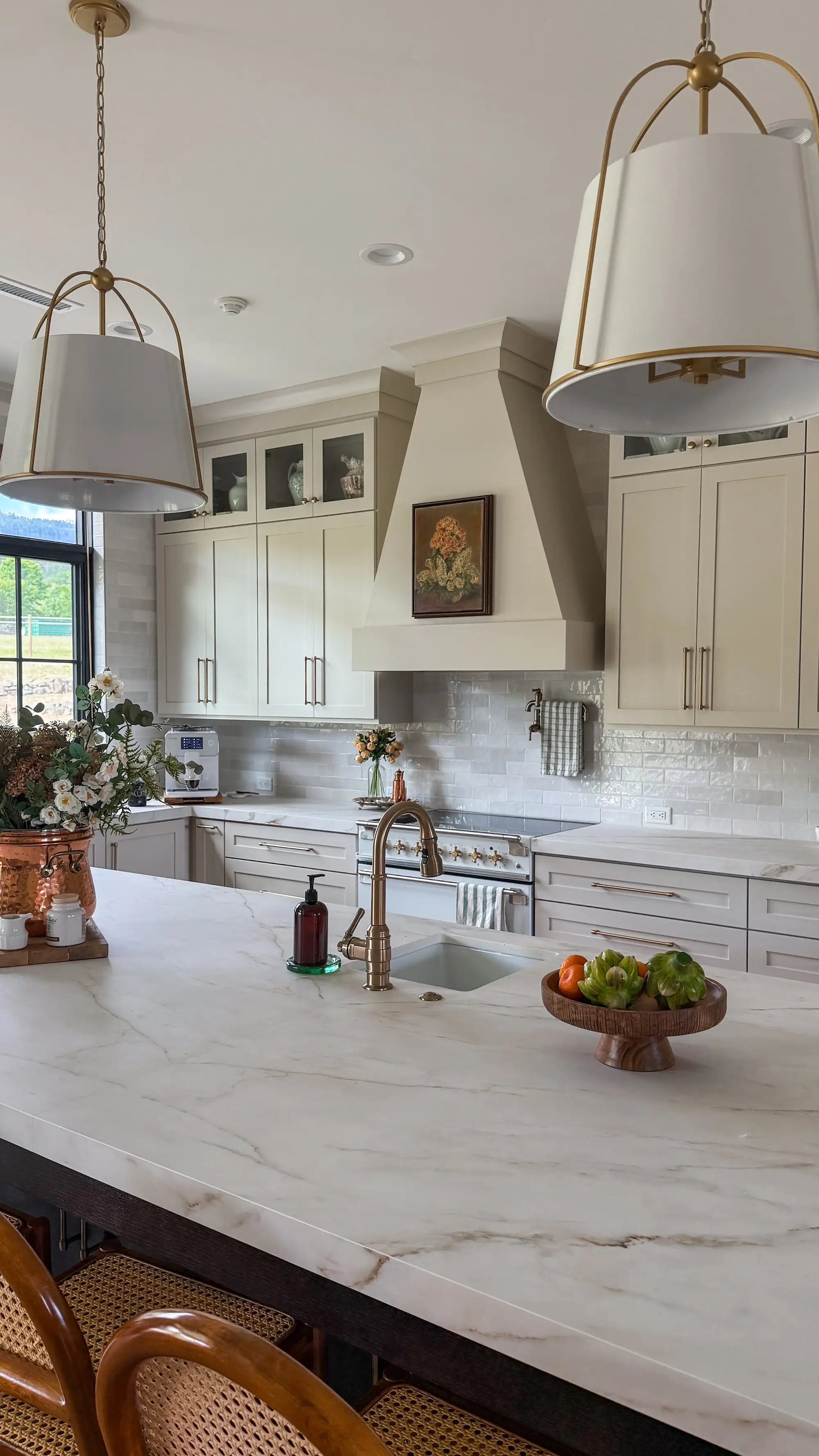 A kitchen with a stone island and off-white cabinets.