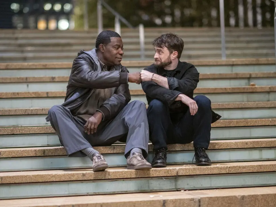 Tracy Morgan and Daniel Radcliffe pounding it while sitting on steps in The Fall and Rise of Reggie Dinkins