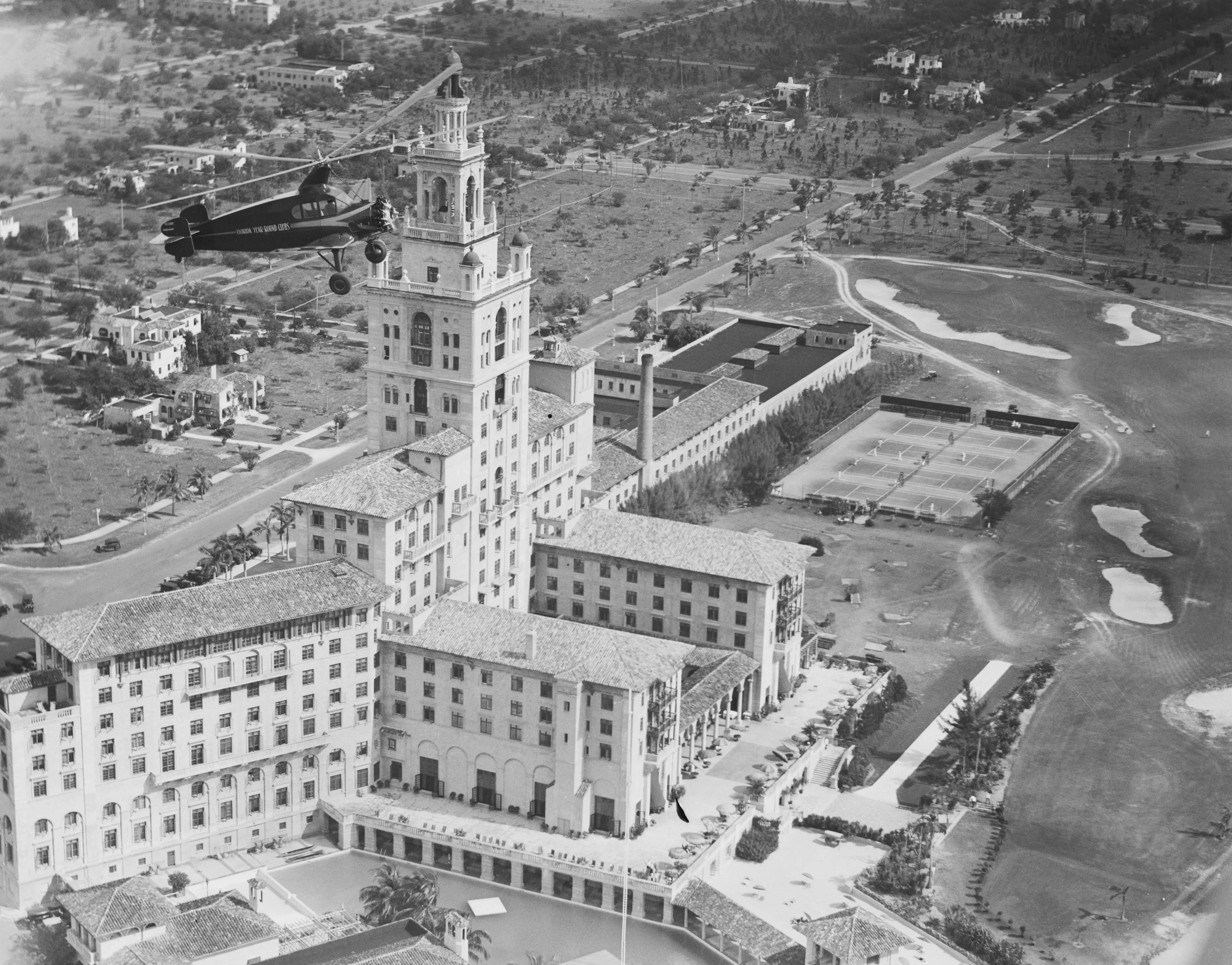Aerial Taxi Service. Hovering high above the Miami Biltmore Hotel in Miami, Florida, the world's largest autogiro, also the first such ship of cabin design, makes its first flight after being inaugurated into aerial taxi service for the Florida Year Round Clubs, at Coral Gables, Florida. The plane will be used for transportation by club members between the club's three units at Miami Beach, Key Largo, and Coral Gables.