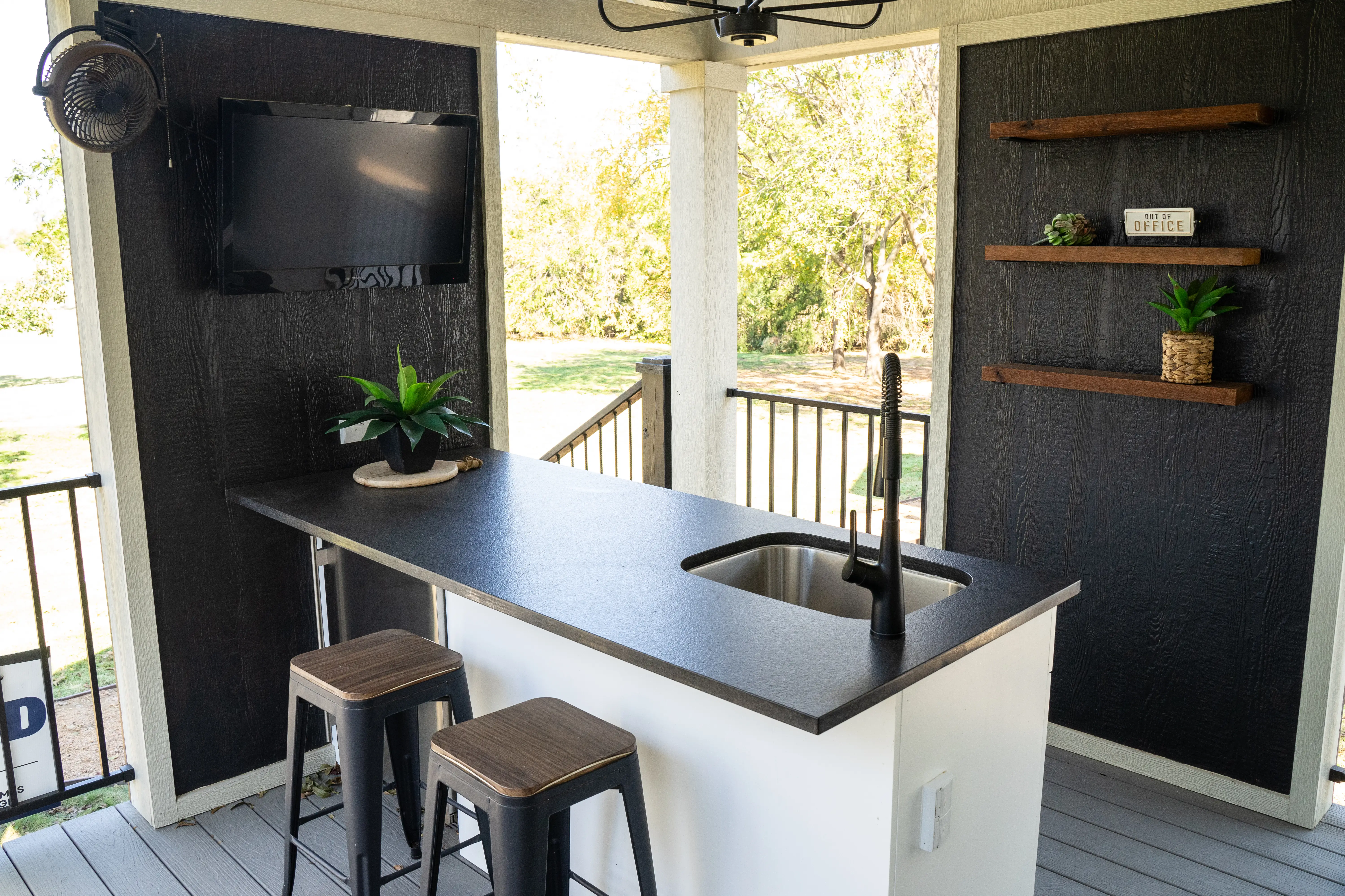 An outdoor kitchen, including a sink and mounted television.