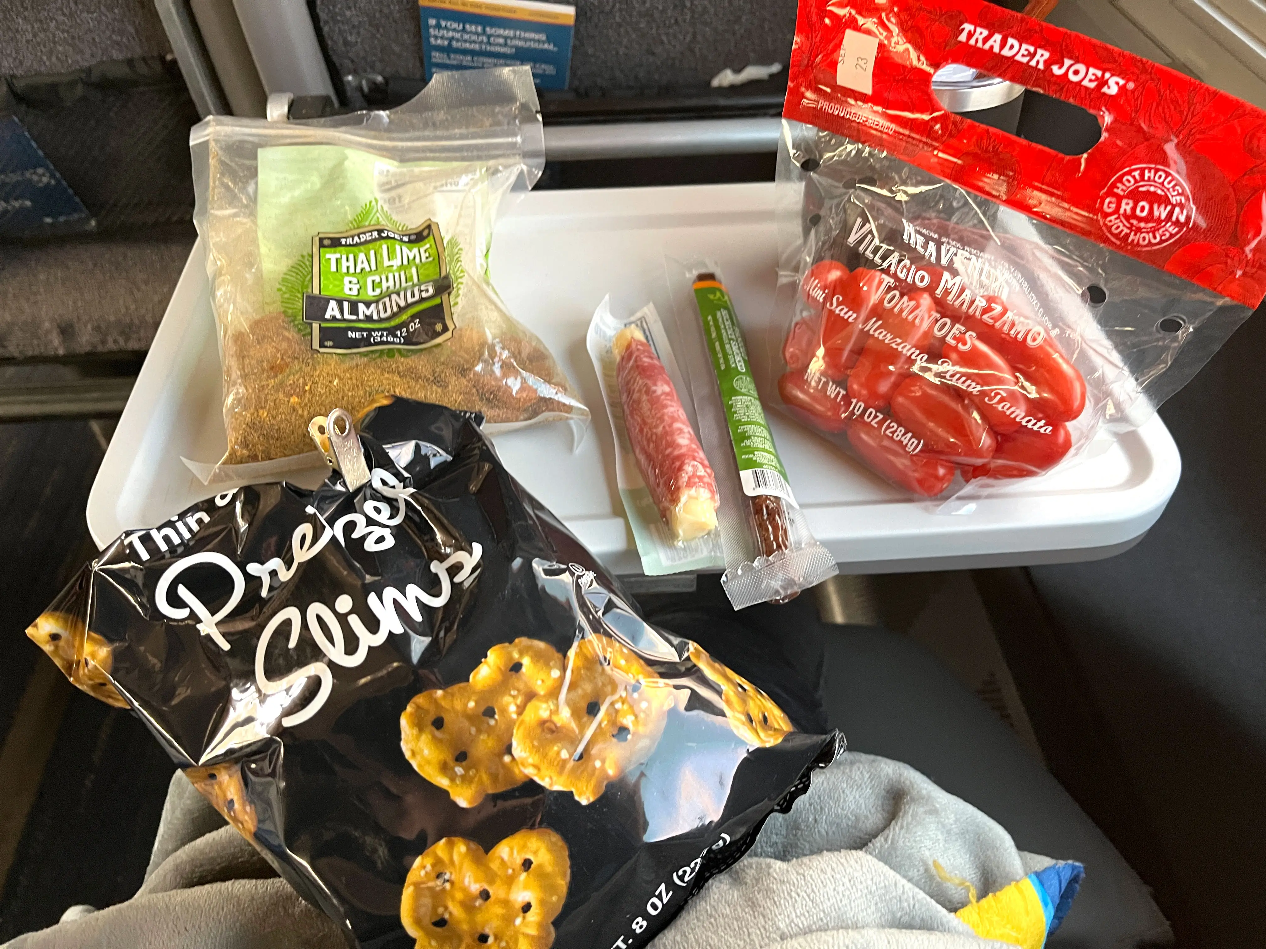 An assortment of snacks from Trader Joe's on the tray table of a train.