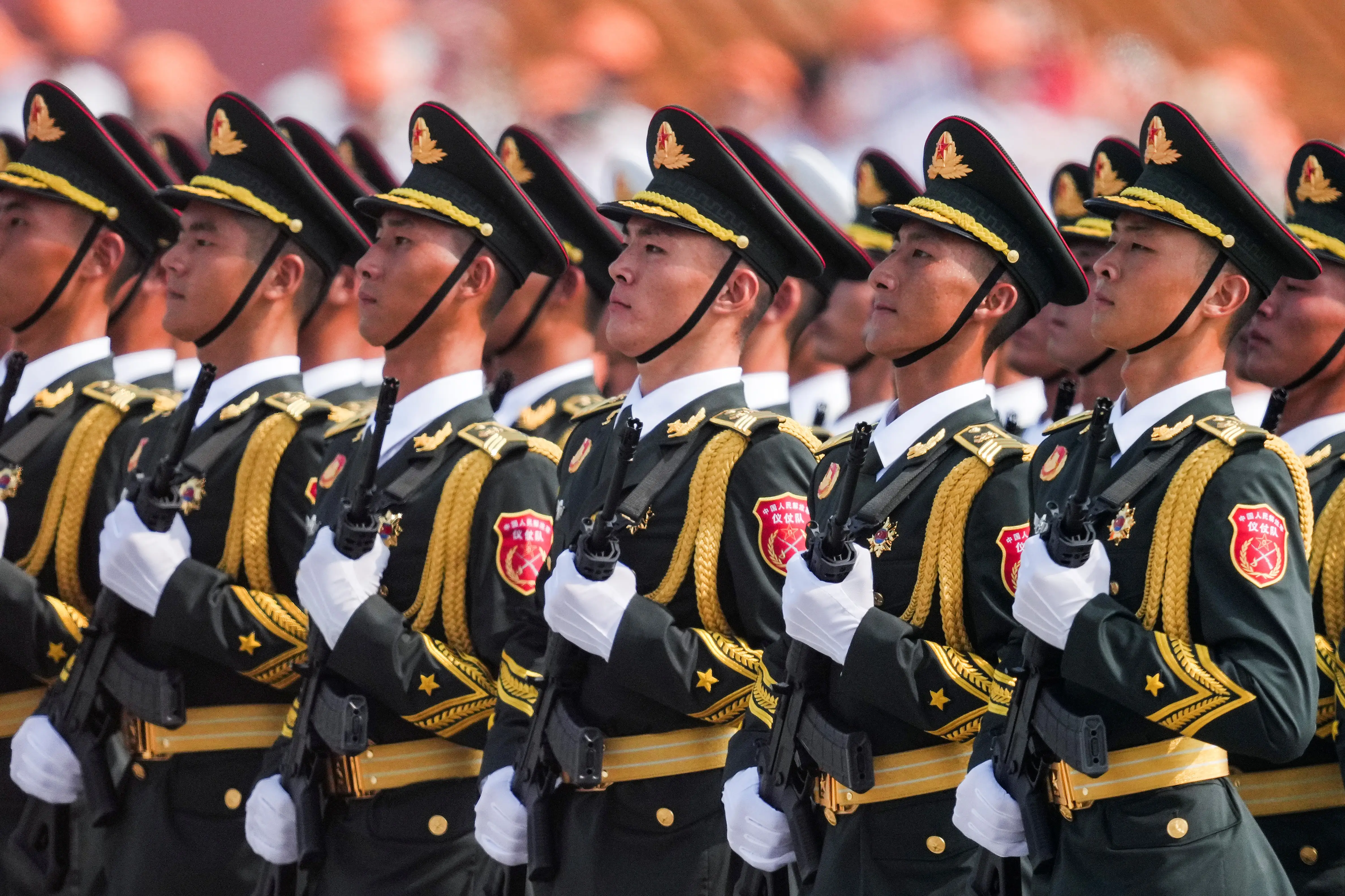 Lines of Chinese soldiers stand wearing uniforms and holding rifles.