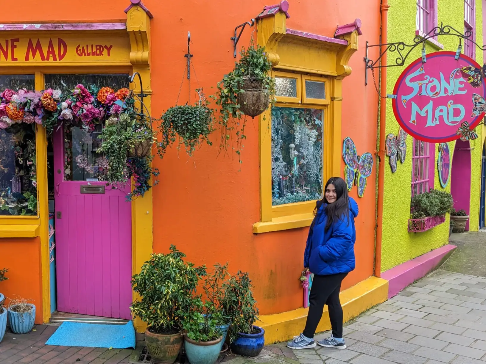 The writer standing in front of a colorful building, Stone Mad Gallery, in Kinsale, Ireland.