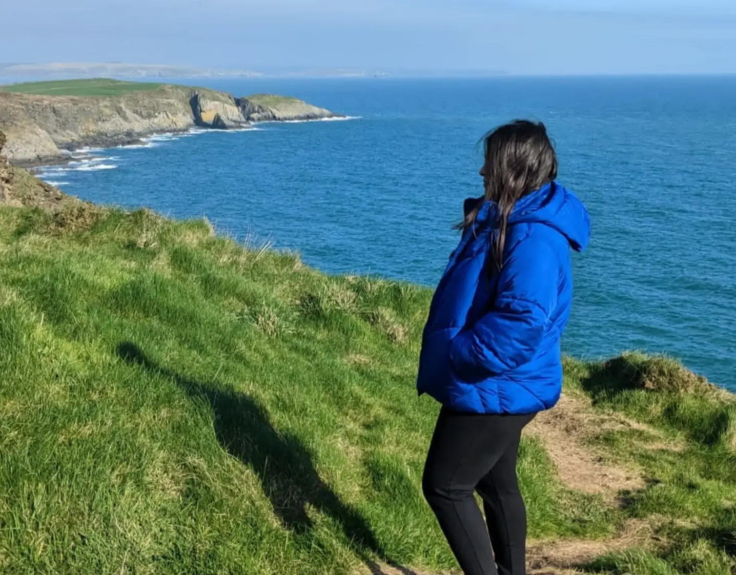 The writer standing in the grass near a body of water in Kinsale, Ireland.