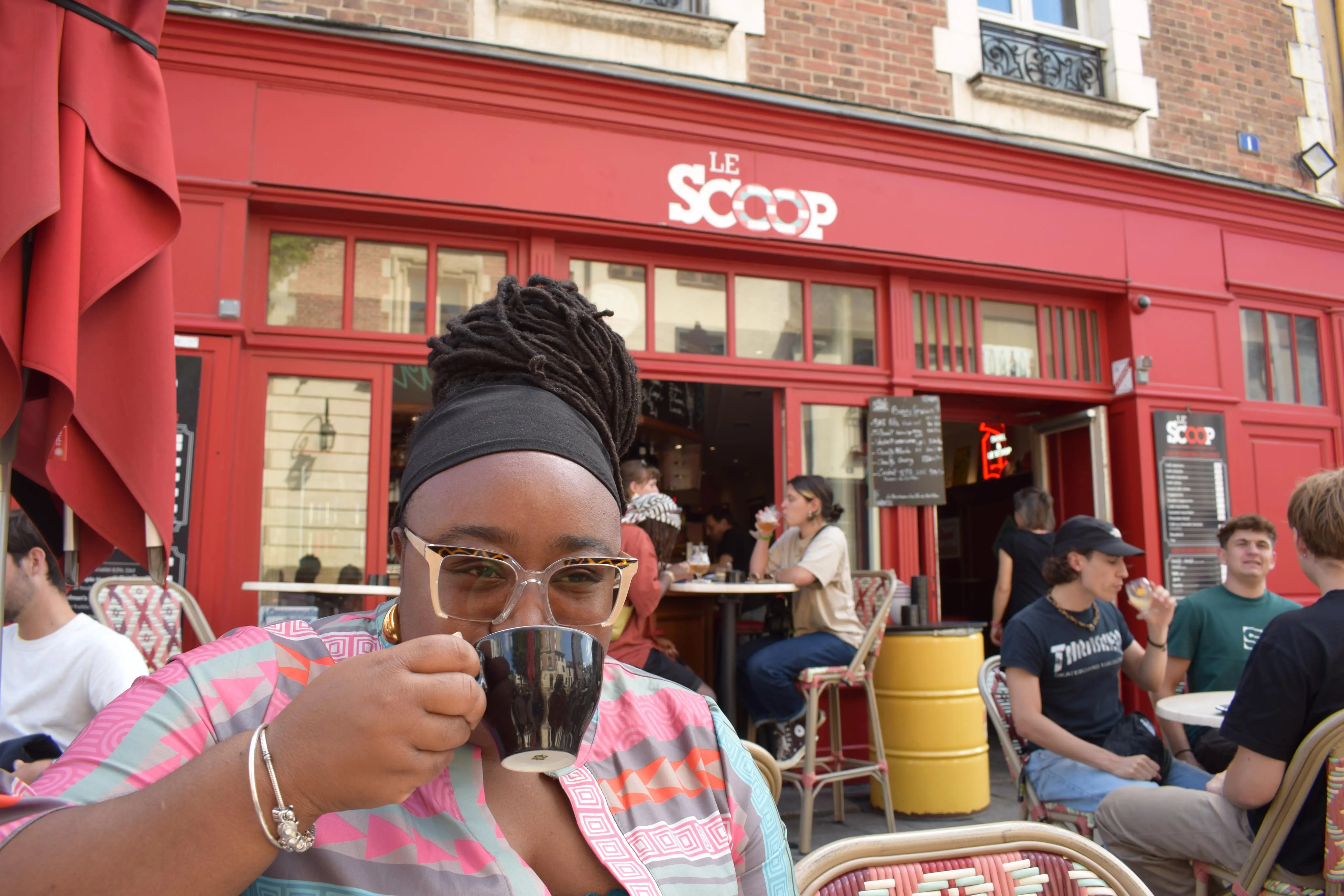 Woman sipping from mug in front of Le Scoop