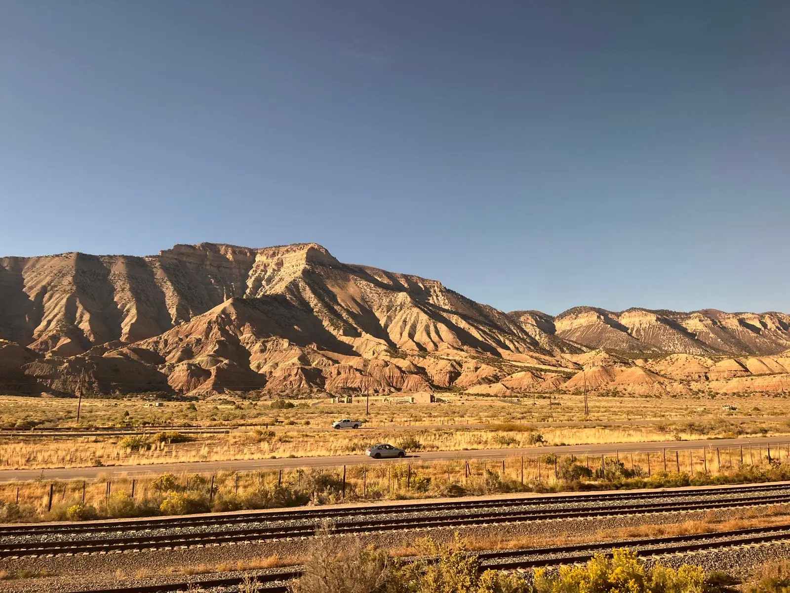 Train tracks and highways with mountains in the background.