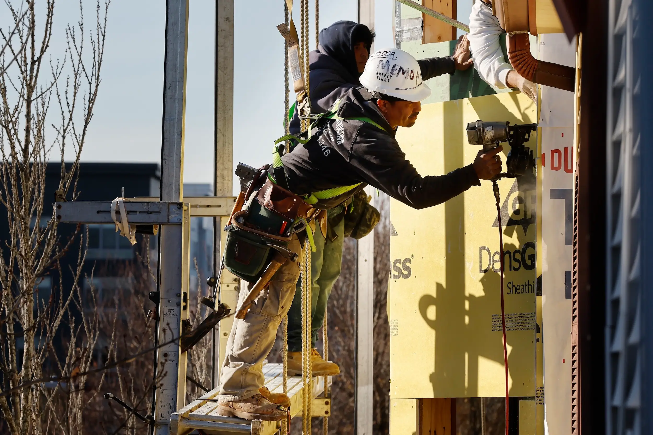 Workers apply sheathing to the exterior of a new multifamily residential building in Boston