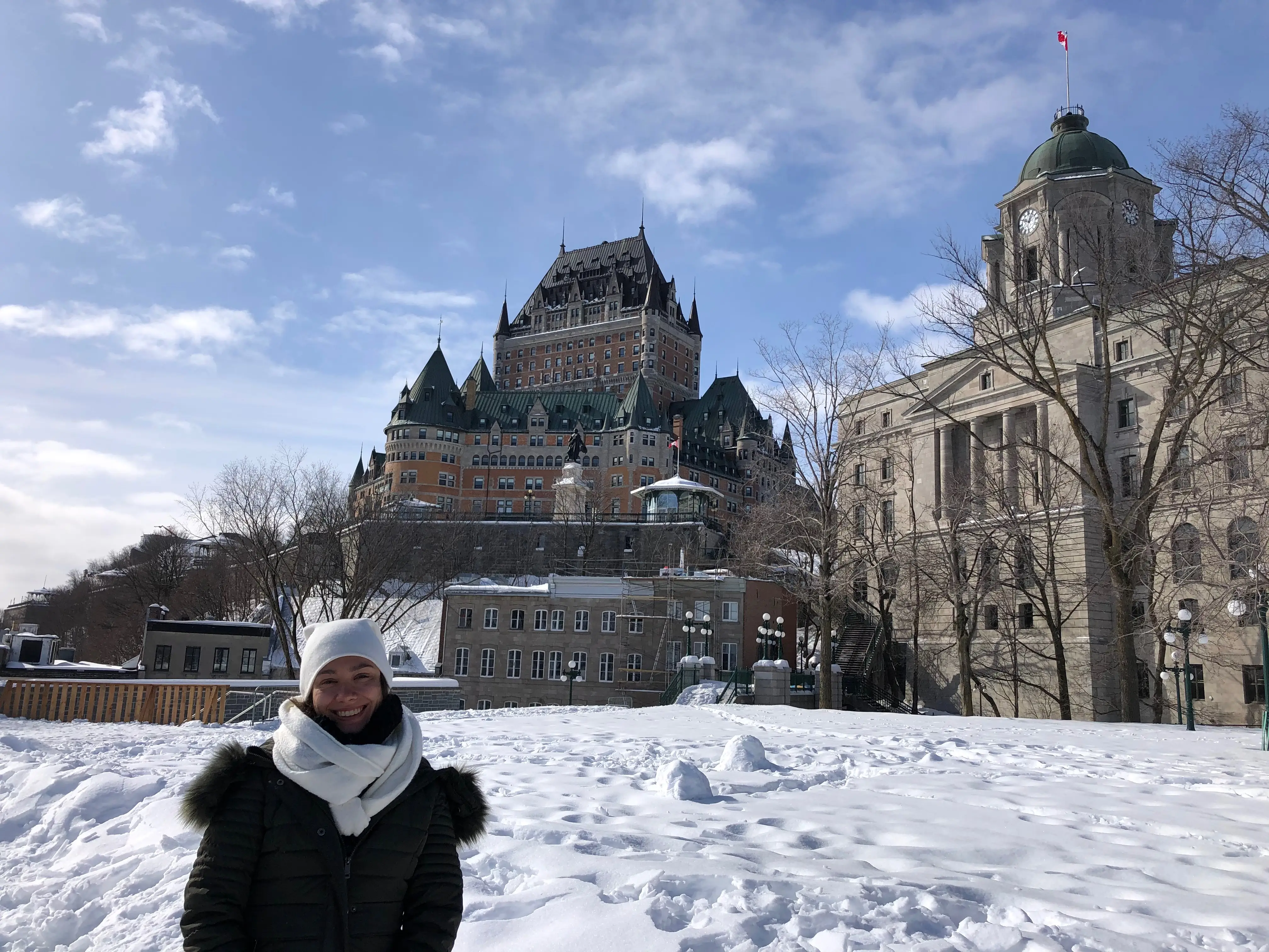 Woman bundled up smiling outside Chateau Frontenac in Quebec City
