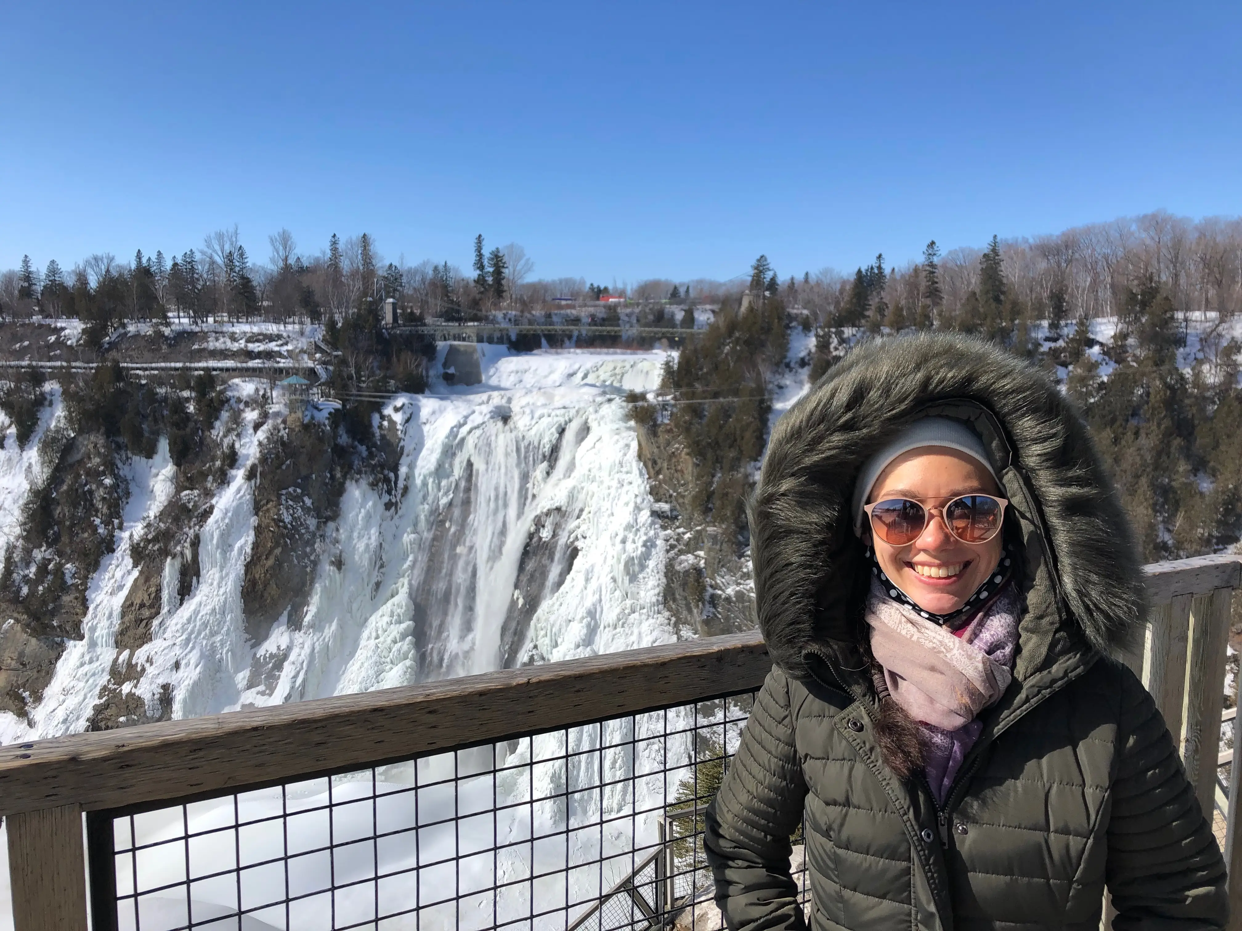 Woman in winter coat smiling at Montmorency Falls  in winter