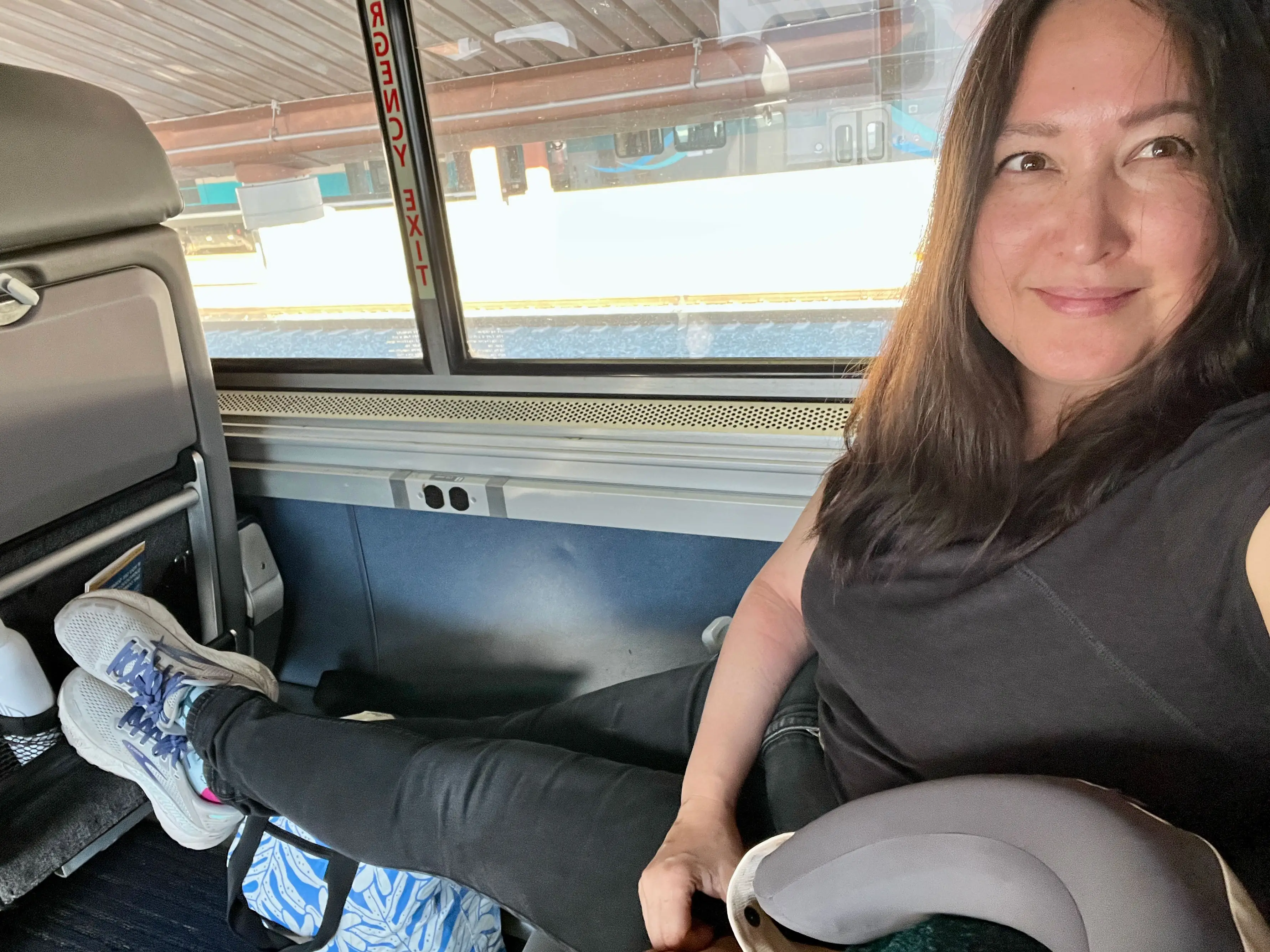 Malia sits in a seat on a train with her legs stretched out.