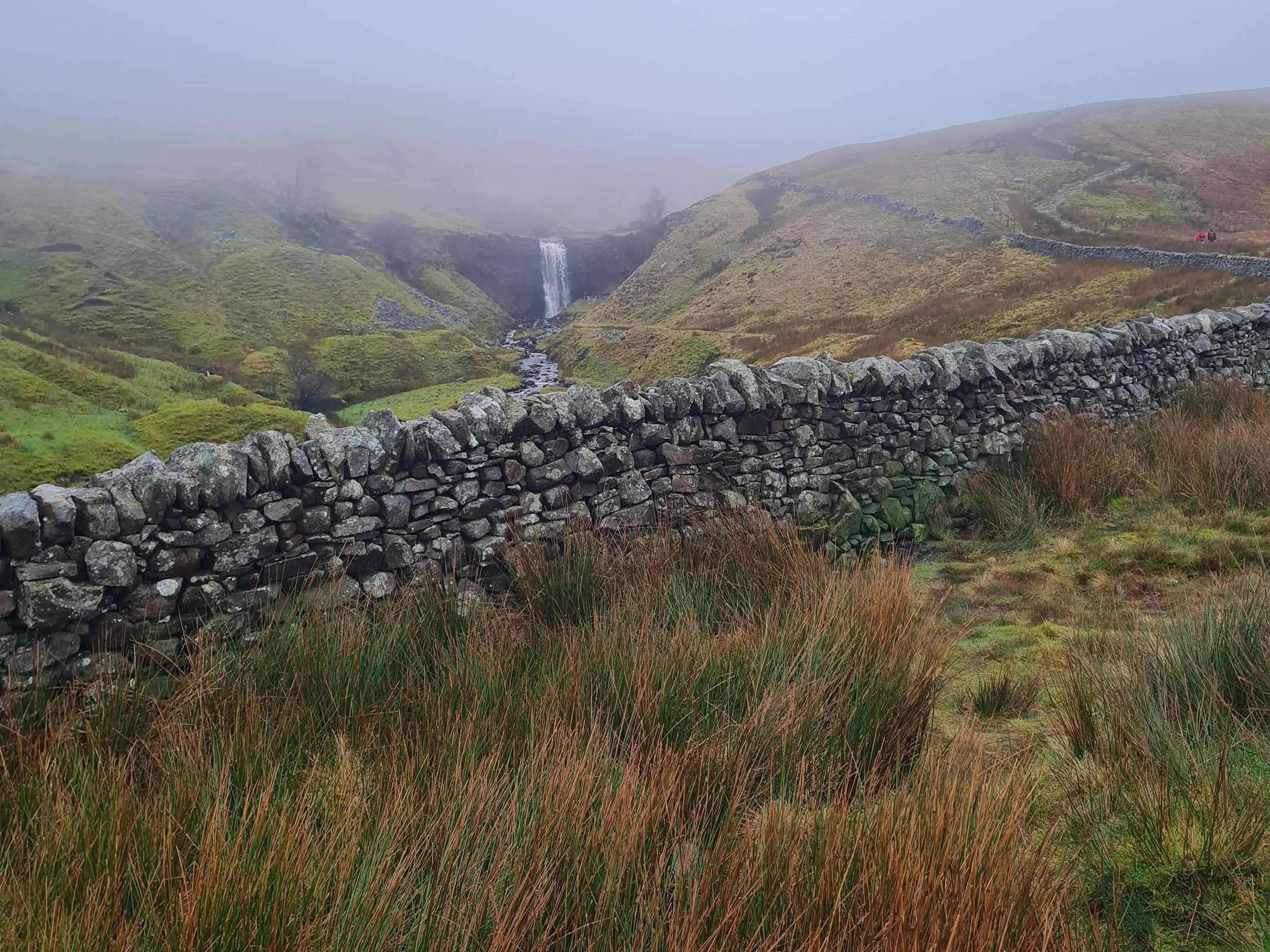 Fog over muddy, grassy area and brick wall