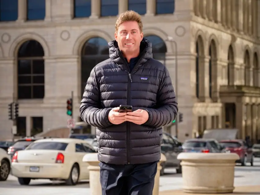 Sam Perry walking while holding his phone.