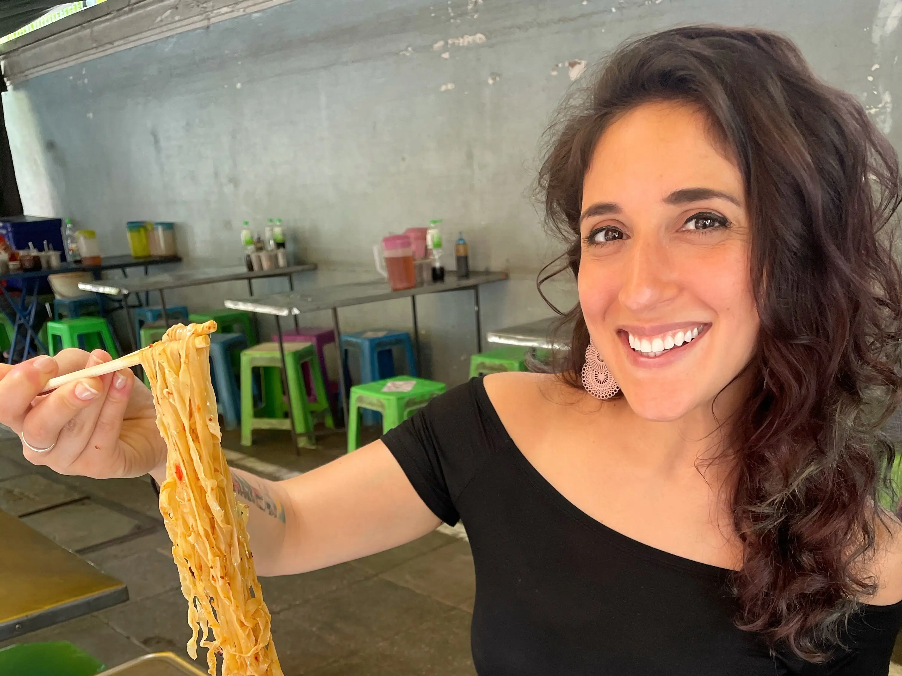 A woman eating a bowl of noodles in Bangkok.