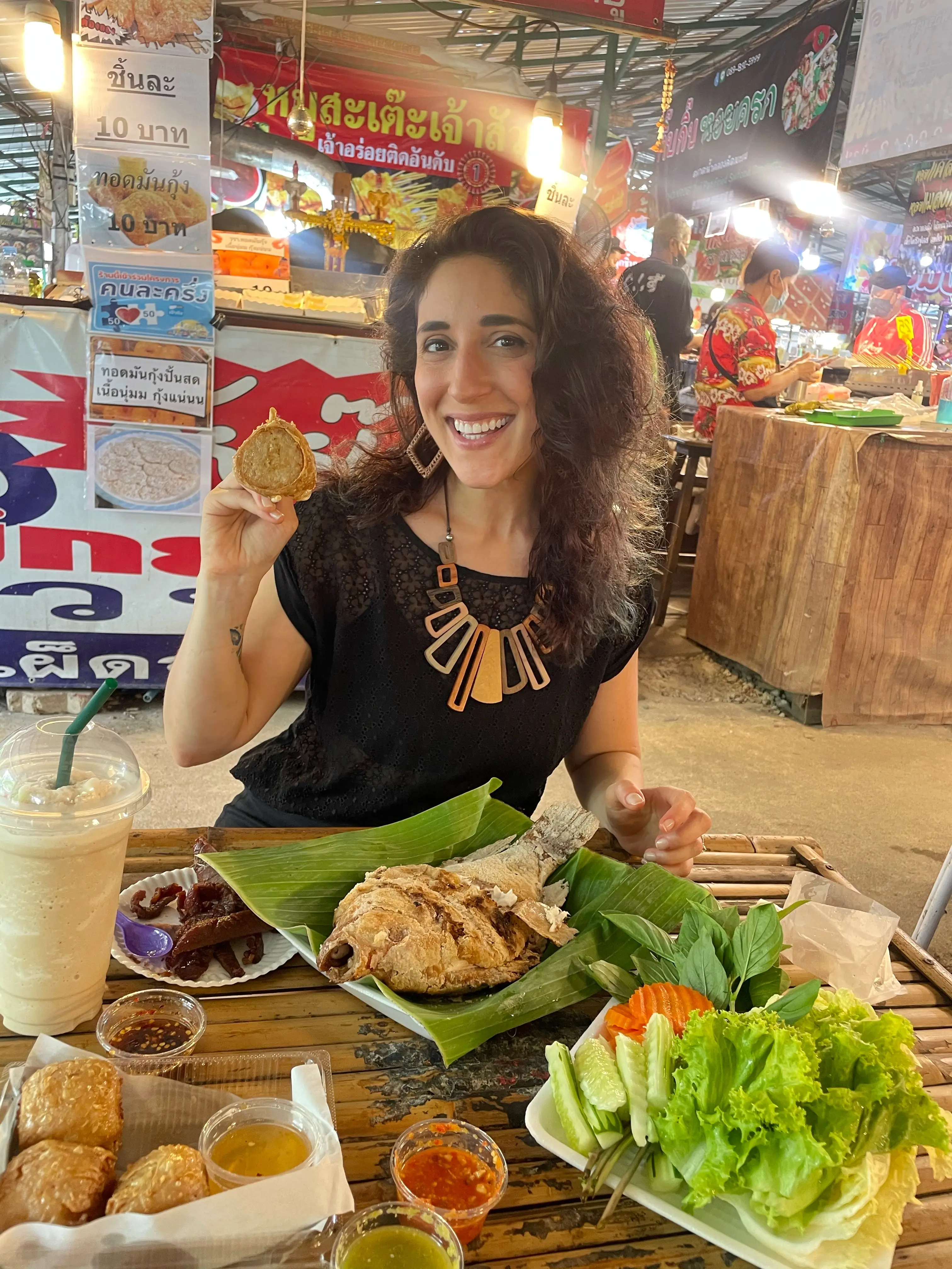 A woman eating at Khlong Lat Malom Market in Bangkok, Thailand.