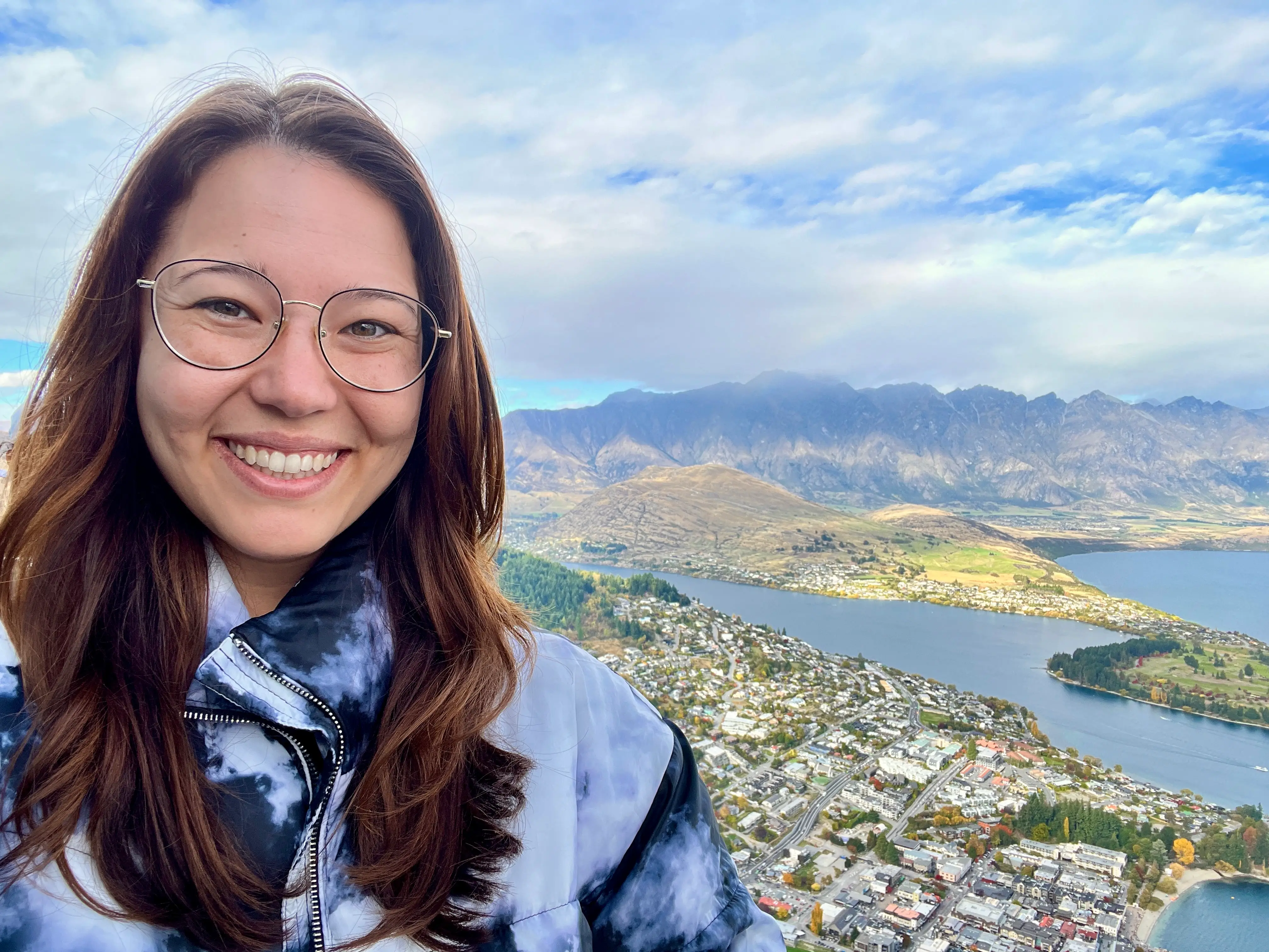 Author Ashley Probst smiling over aerial view of New Zealand