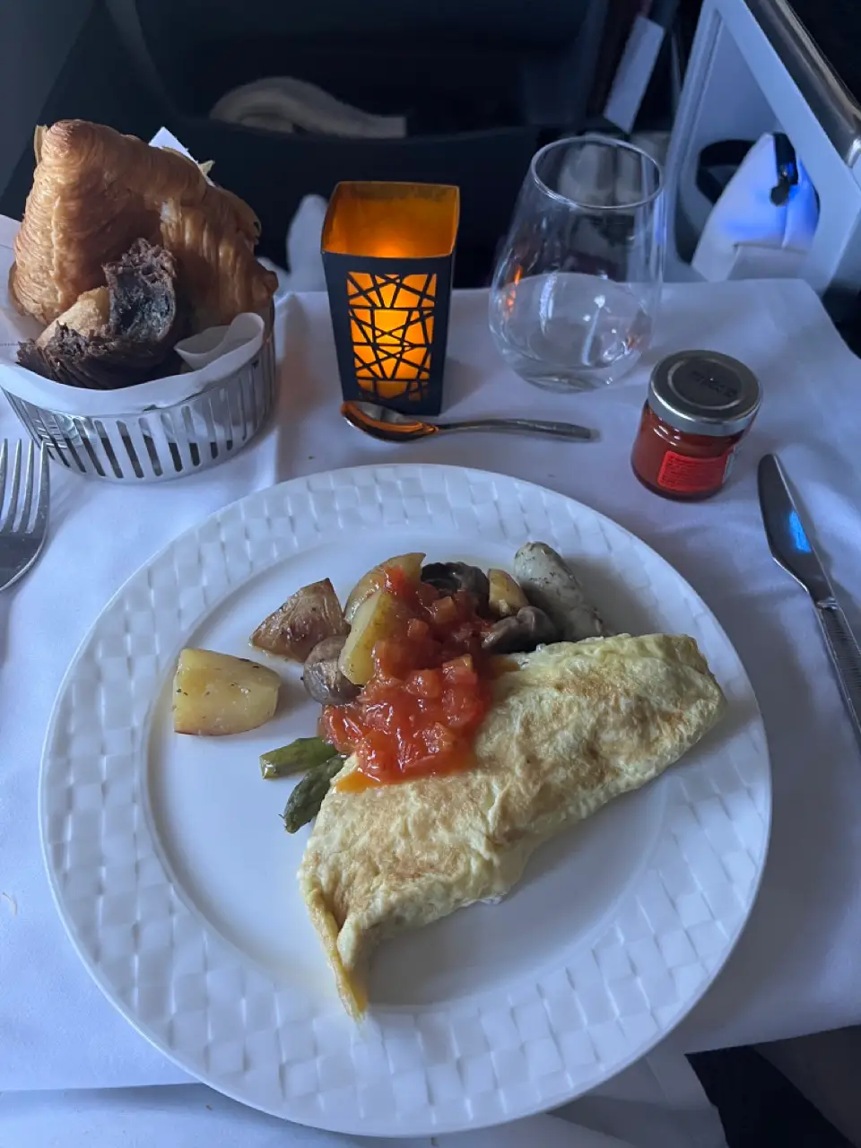 Omelet on plate on tray table on plate with side basket with muffin, croissant