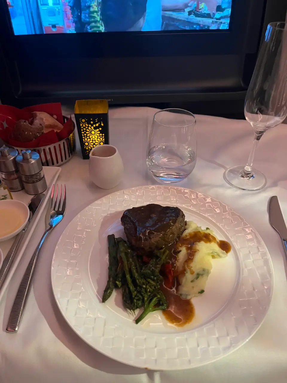 Beef, vegetables, mashed potatoes on tablecloth-covered tray table on flight
