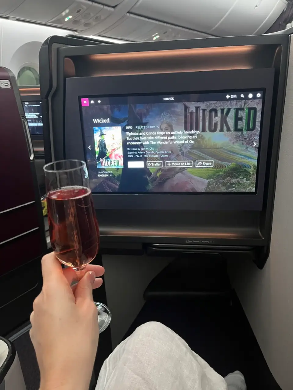 Glass of wine in front of airplane screen showing 