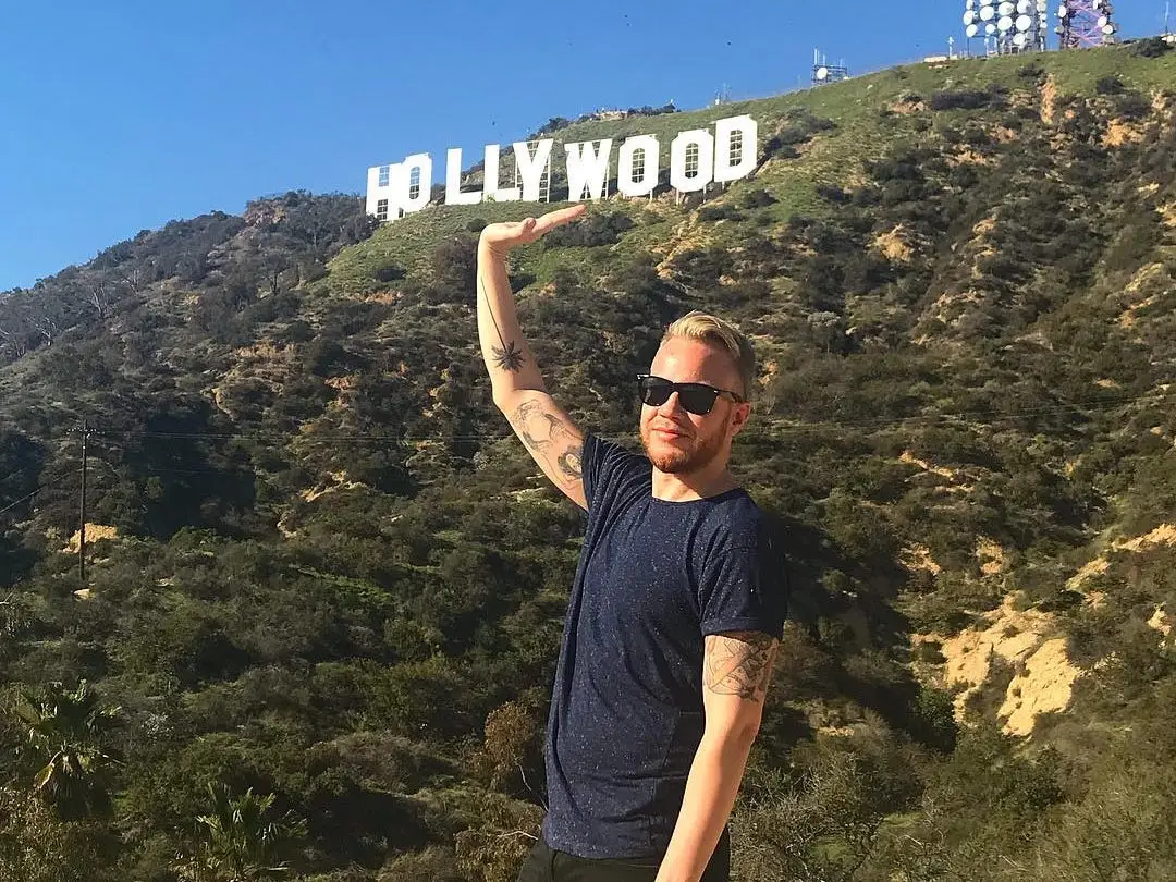 Man posing by the Hollywood sign in Los Angeles, California.