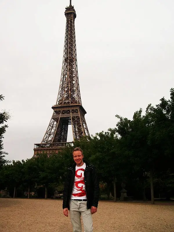 Man standing outside with the Eiffel Tower in the background in Paris, France.