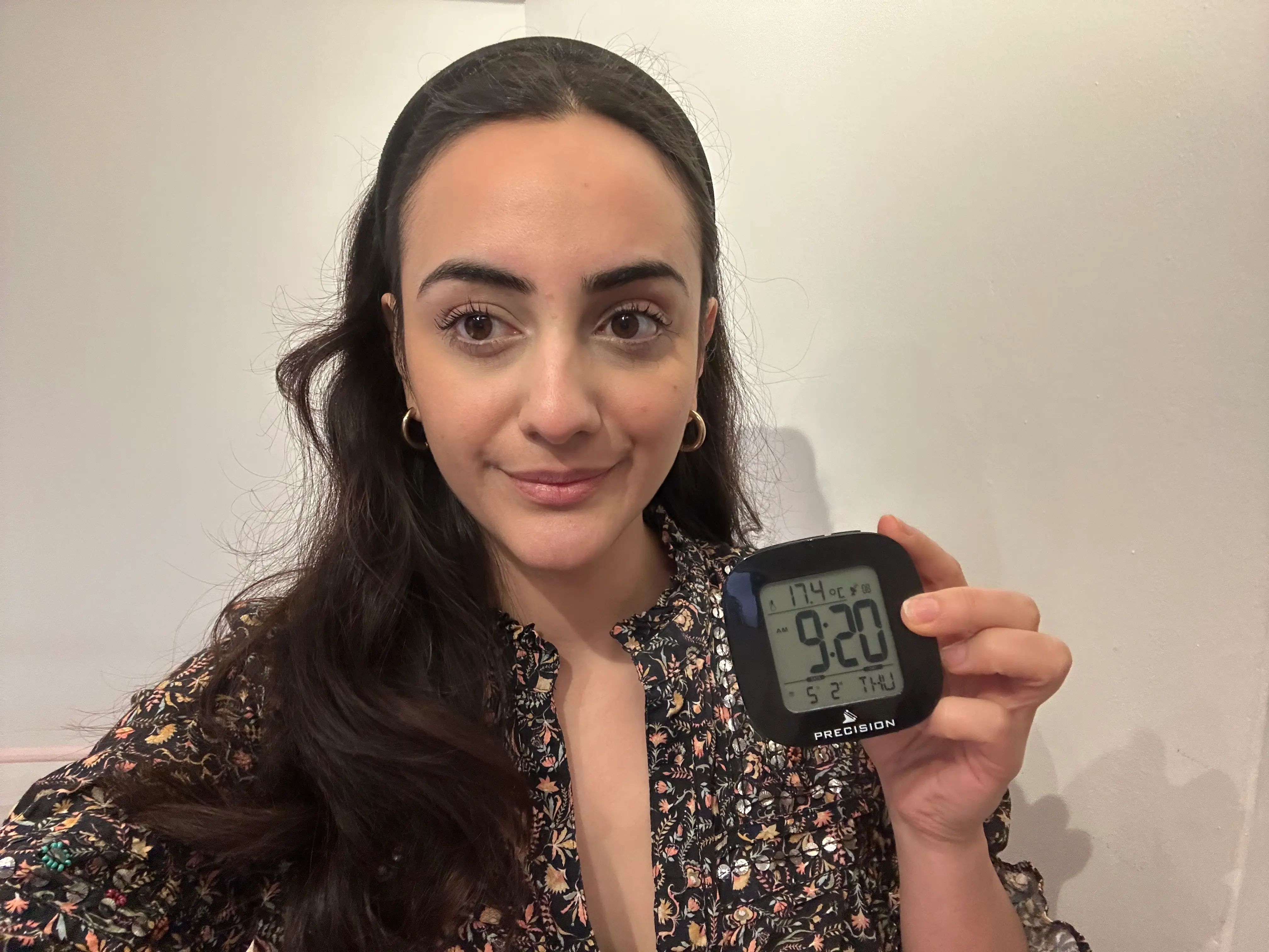 Roya Shahidi poses with analog alarm clock in bedroom