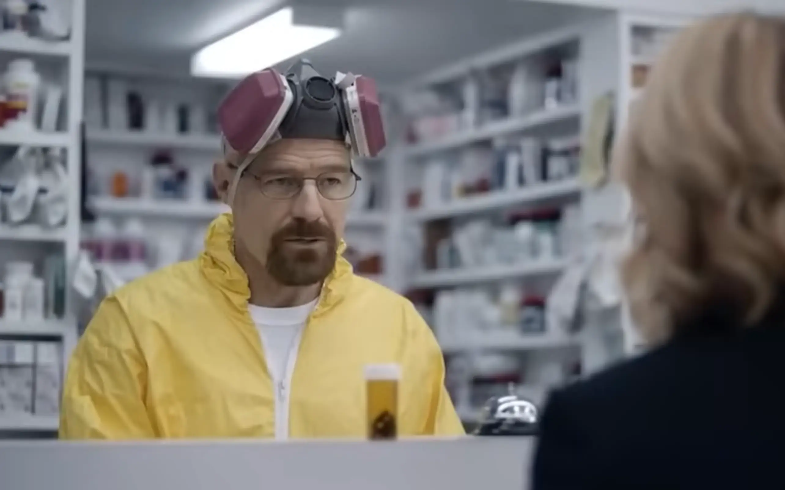 Bryan Cranston, dressed in his Breaking Bad getup, hands a woman a bottle of pills.