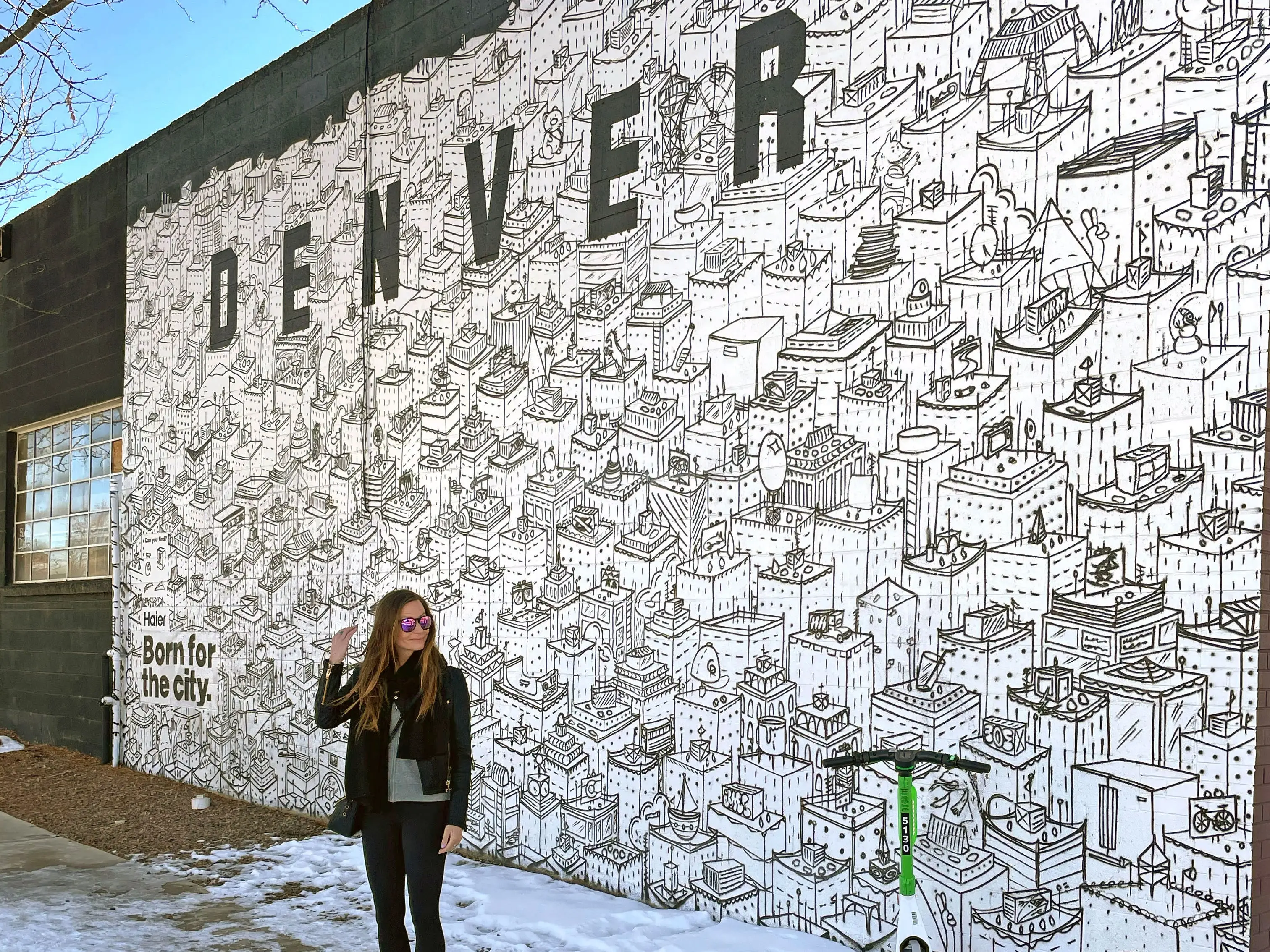 Emily stands in front of a mural that says 