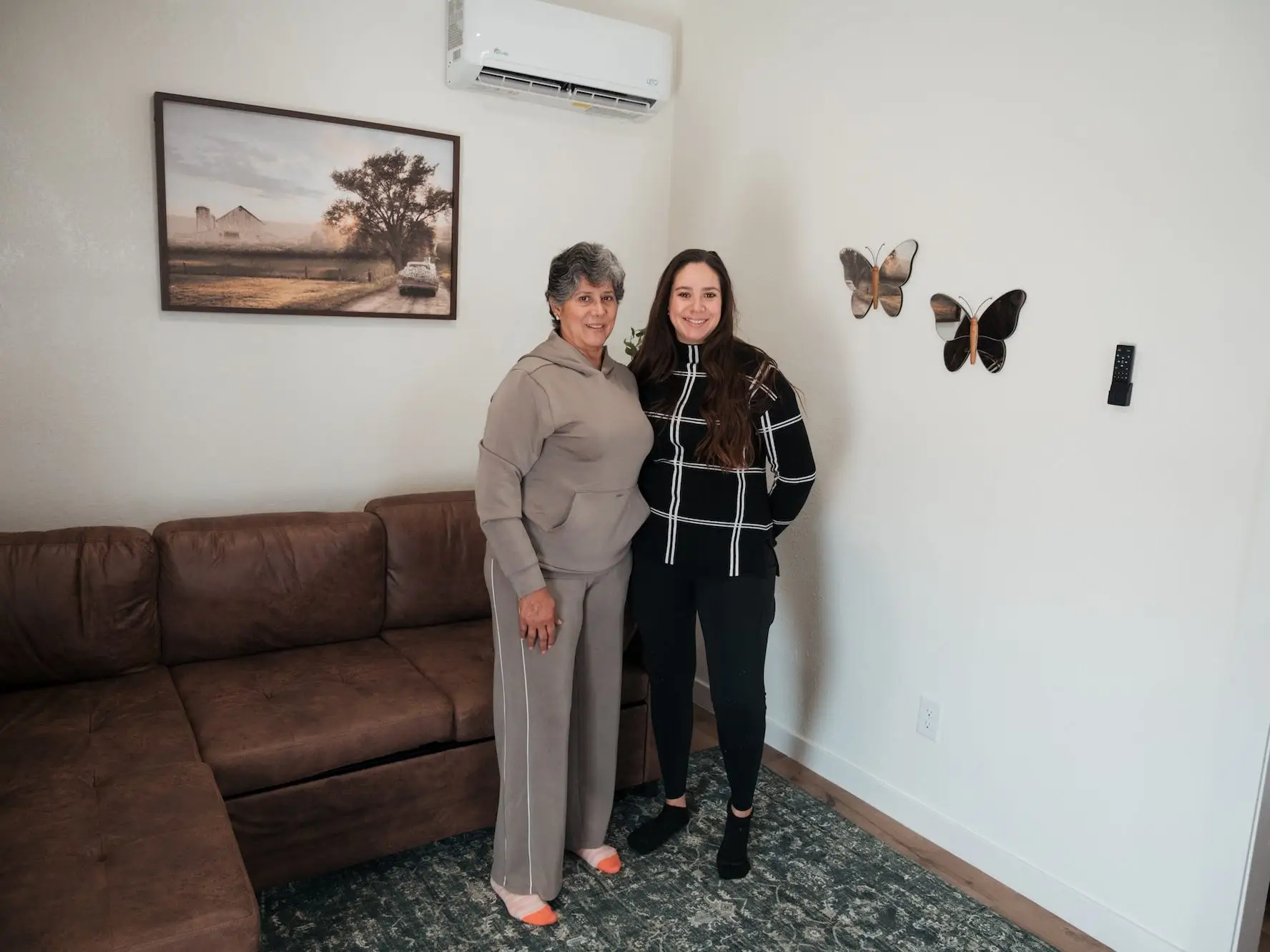 A mother and daughter stand together in a living area.