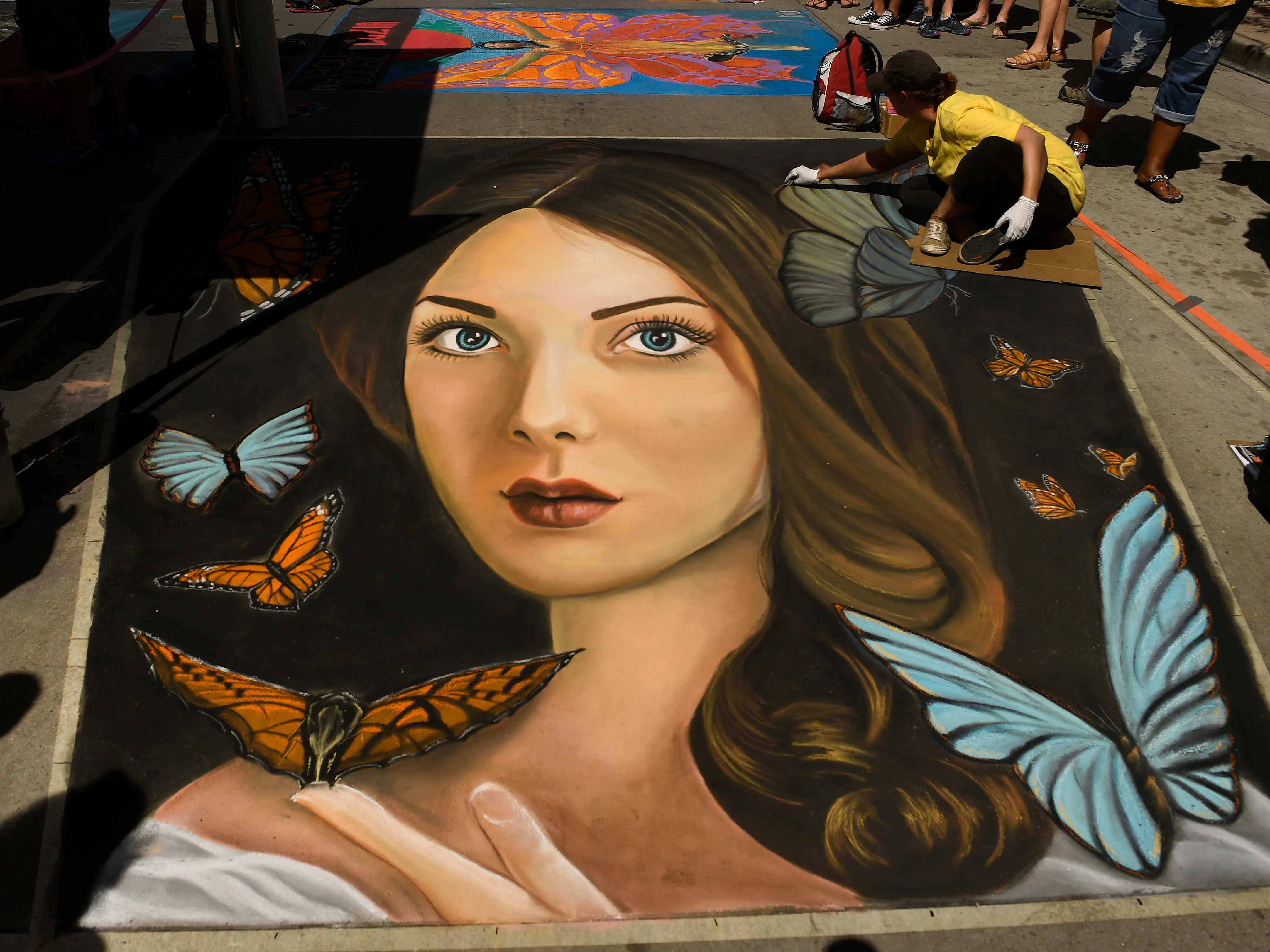 A realistic chalk portrait of a woman and butterflies.