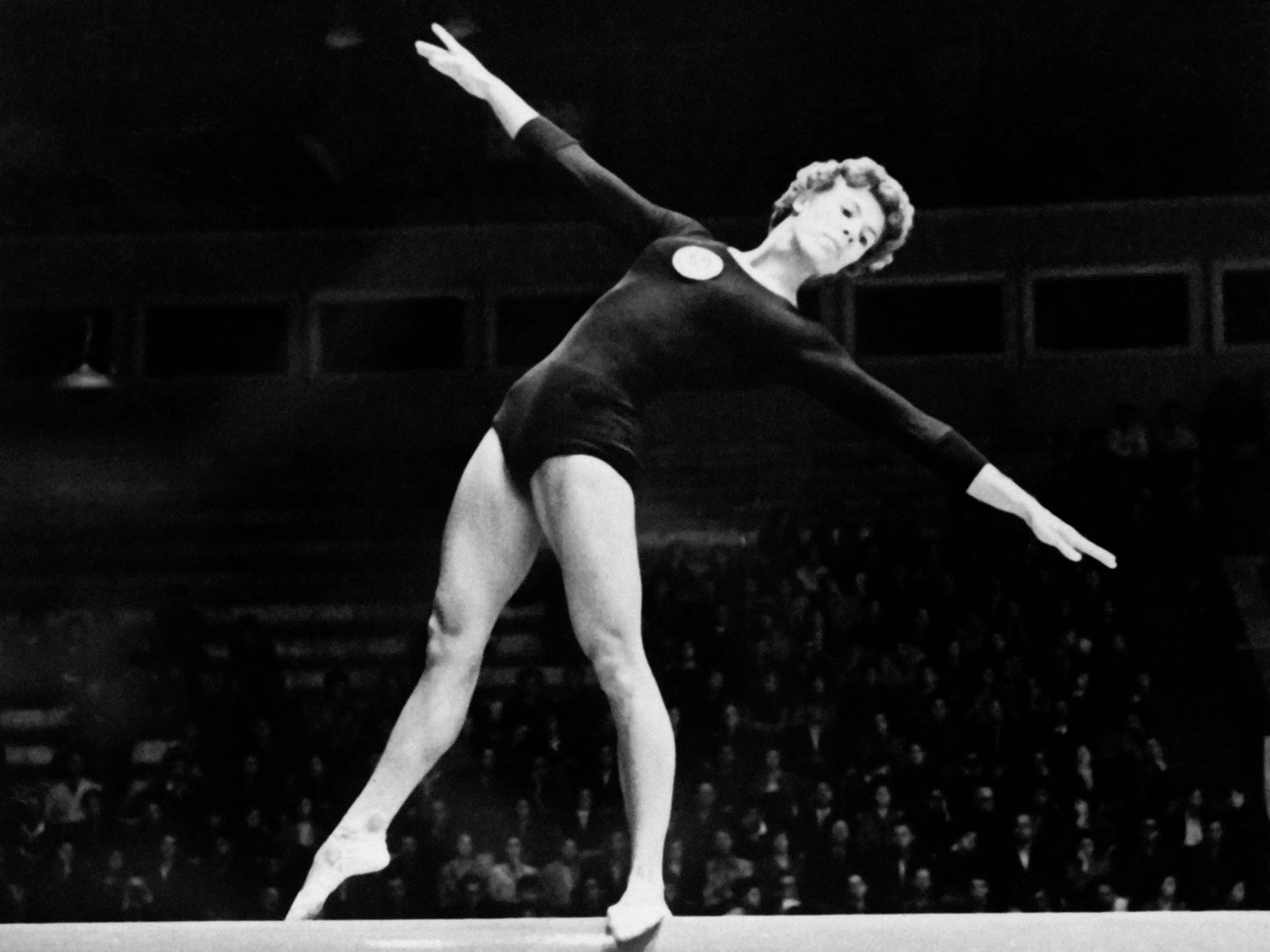 Larisa Latynina of the USSR competed on the balance beam as a crowd of spectators watched.