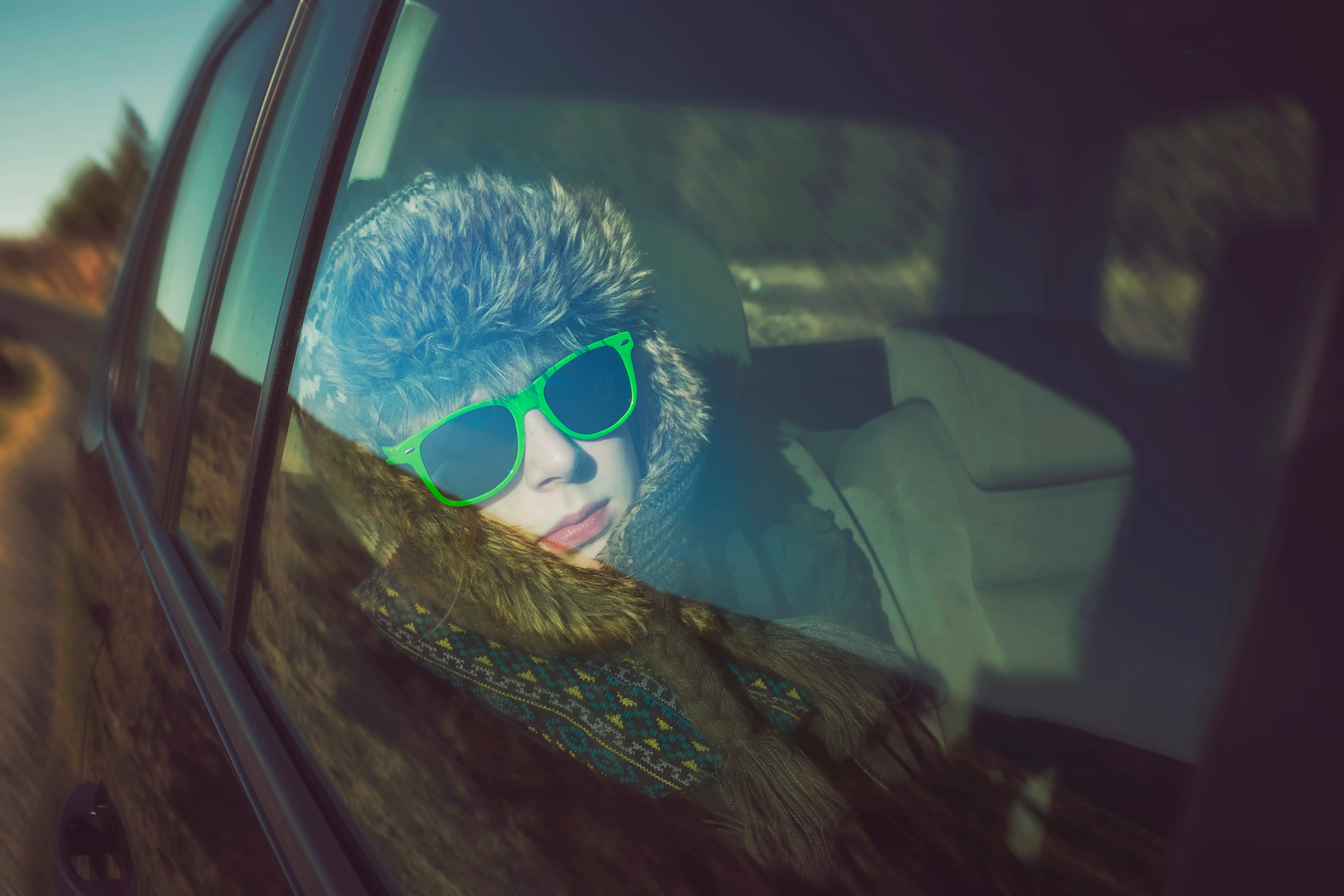 A teenager in the back of a car