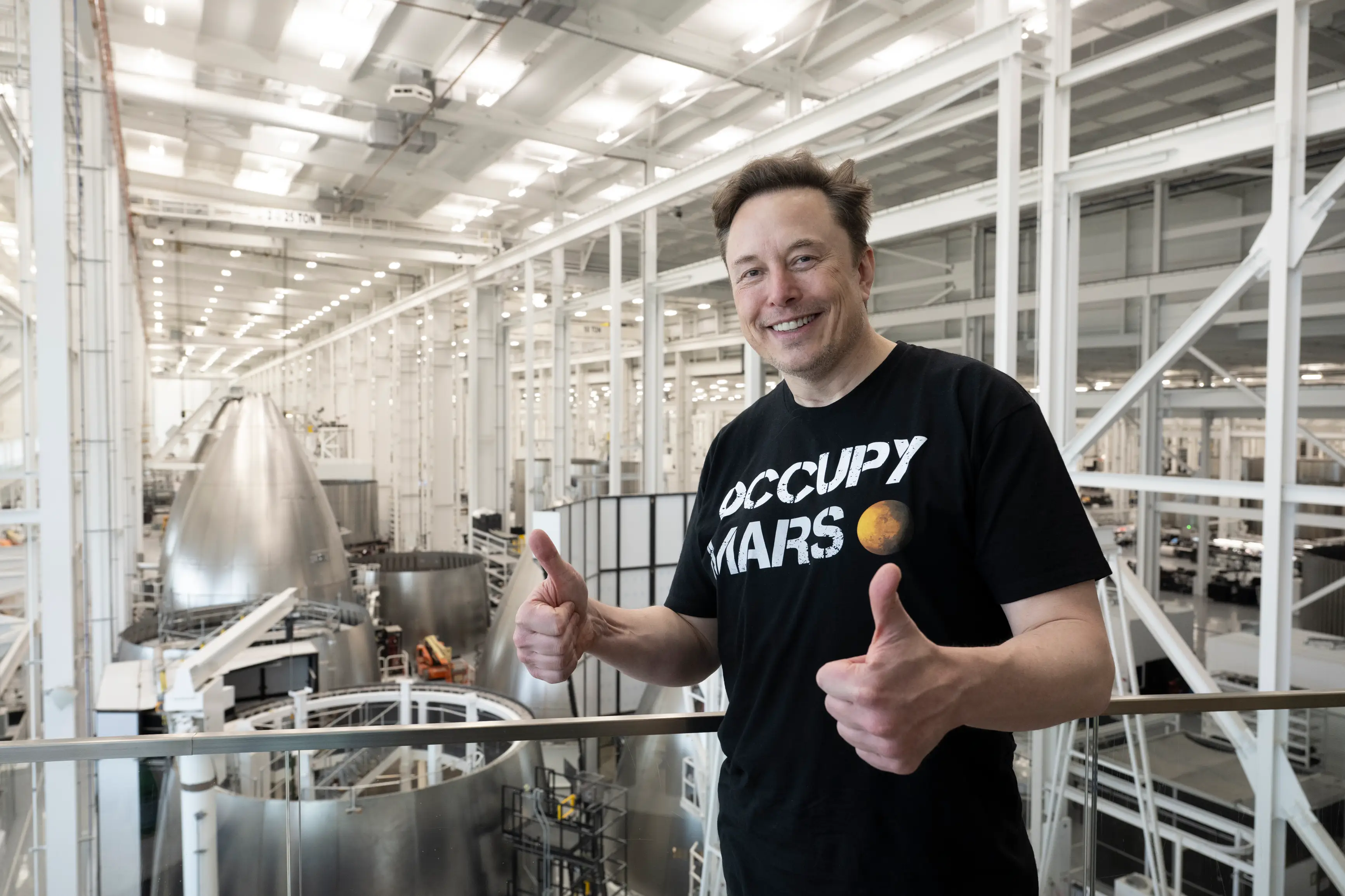 Elon Musk is in a black T-shirt that reads 
