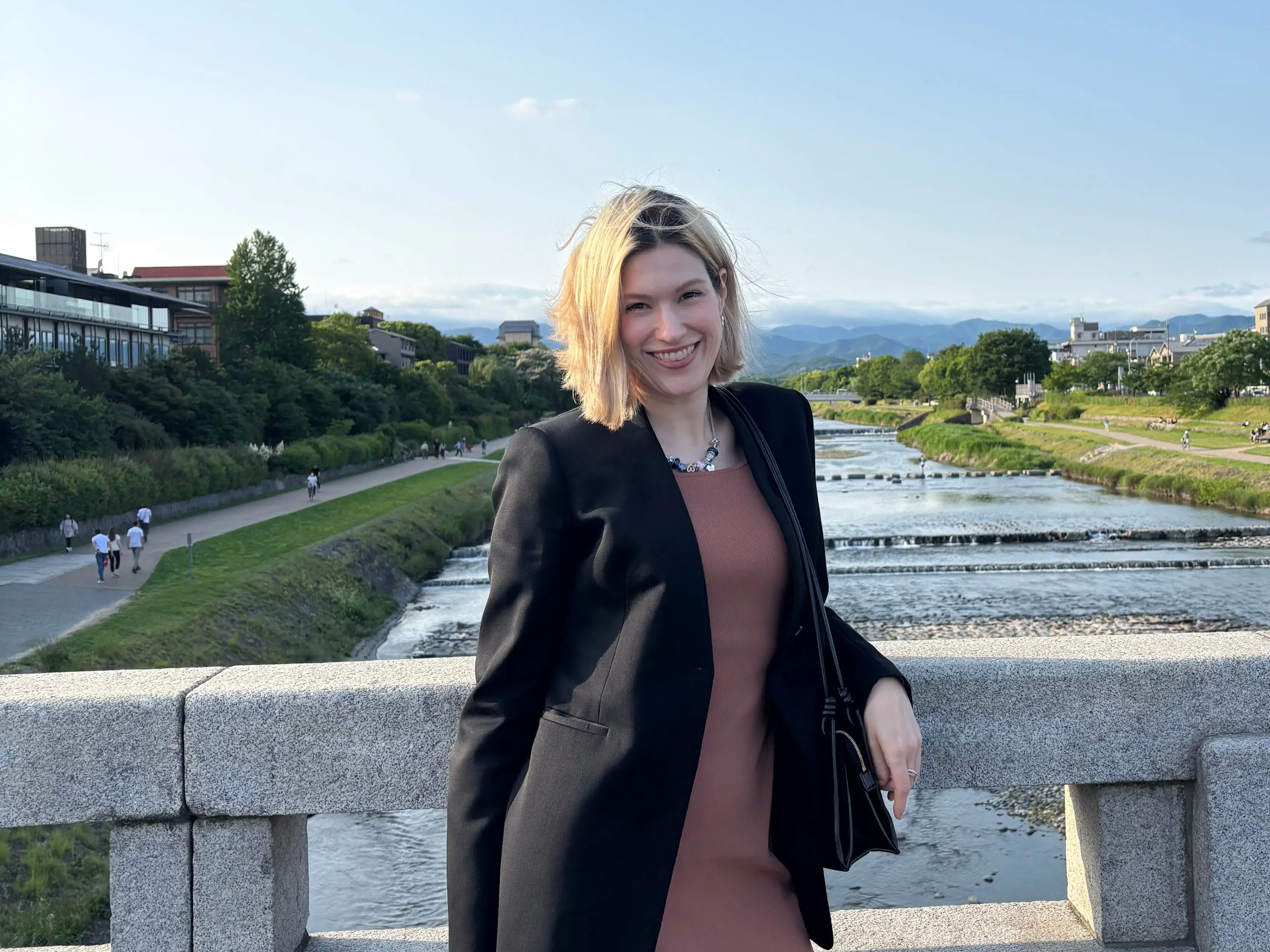 A woman in a black blazer standing on a bridge in Japan.