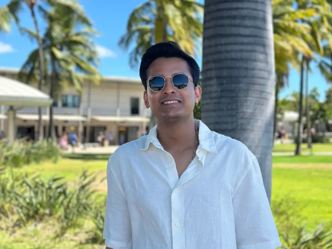 Goswami is standing in front of some palm trees.