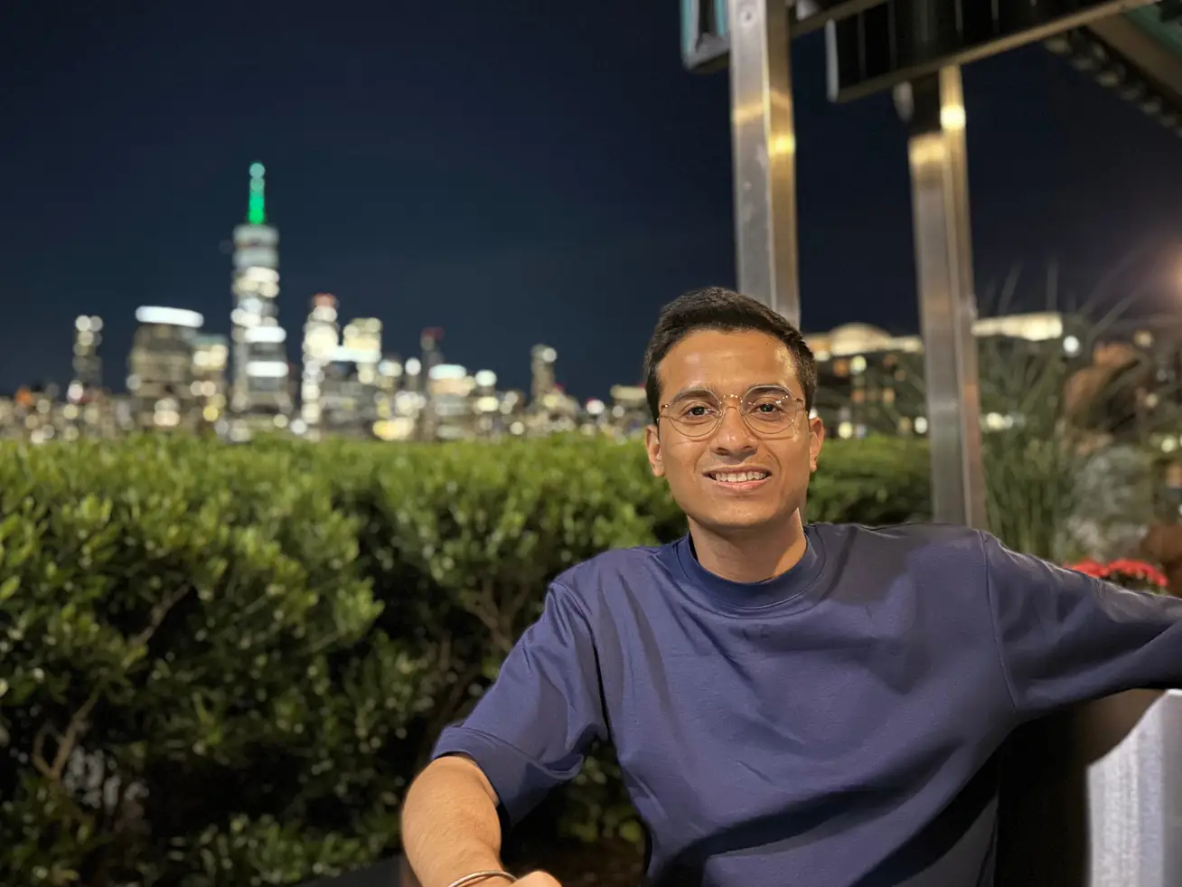 Pronnoy Goswami is sitting outdoors at night, wearing a blue t-shirt.