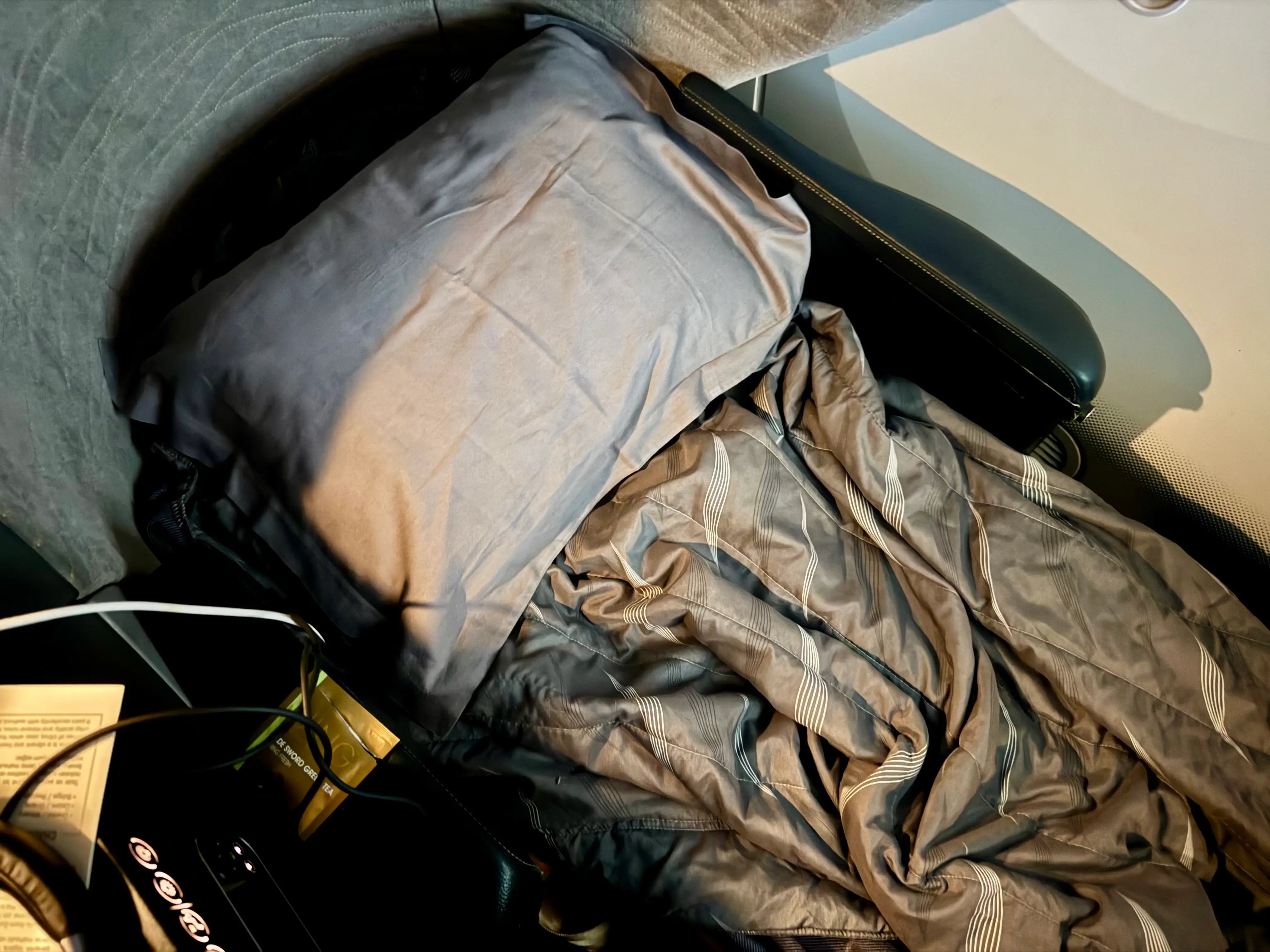 The author's seat in lie flat mode with the grey pillow and brown comforter.