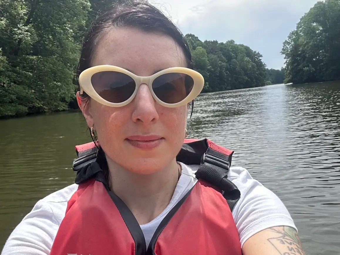 Woman with sunglasses, life vest on body of water