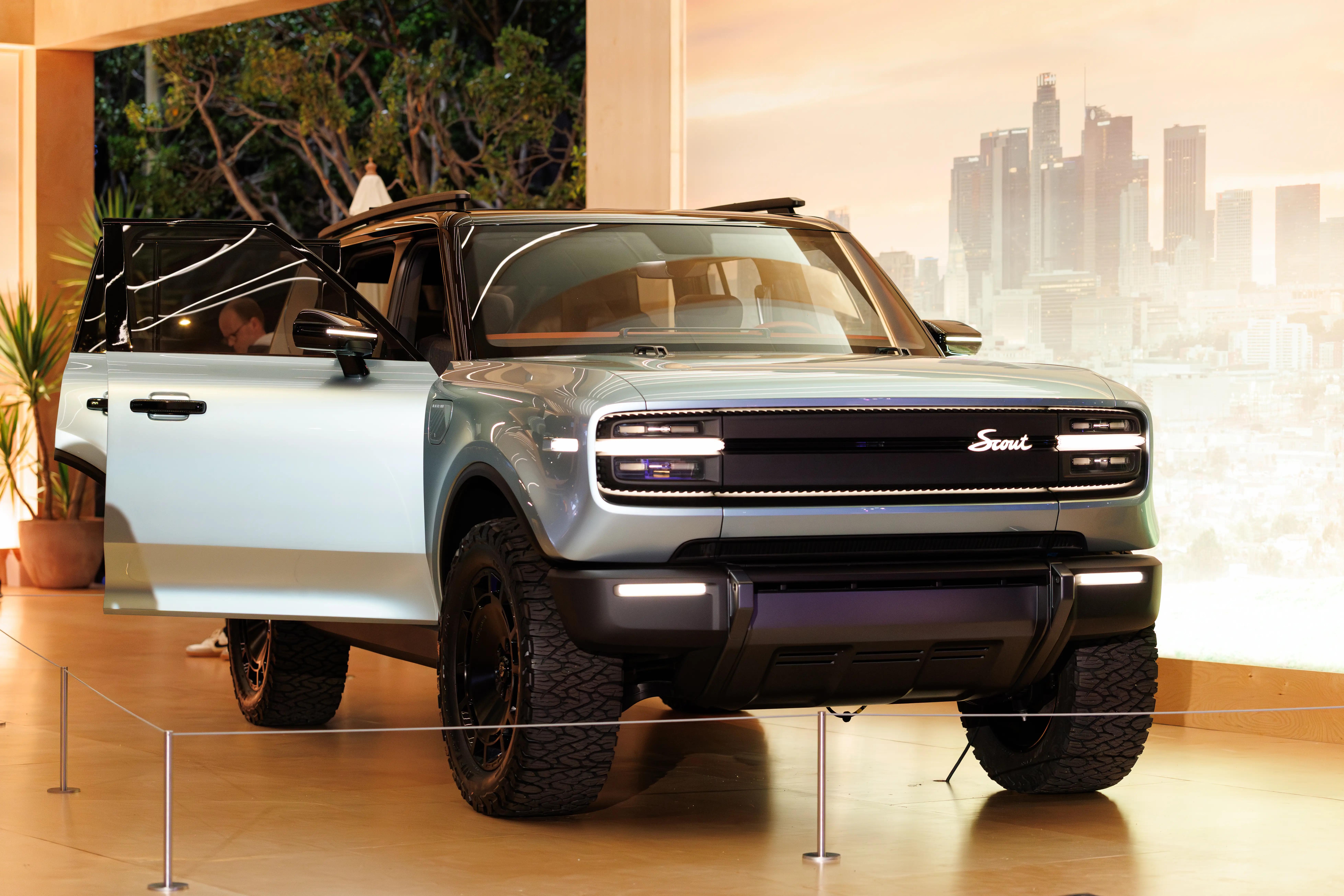 A silver Scout Traveler SUV is parked behind a stanchion on a wooden floor.