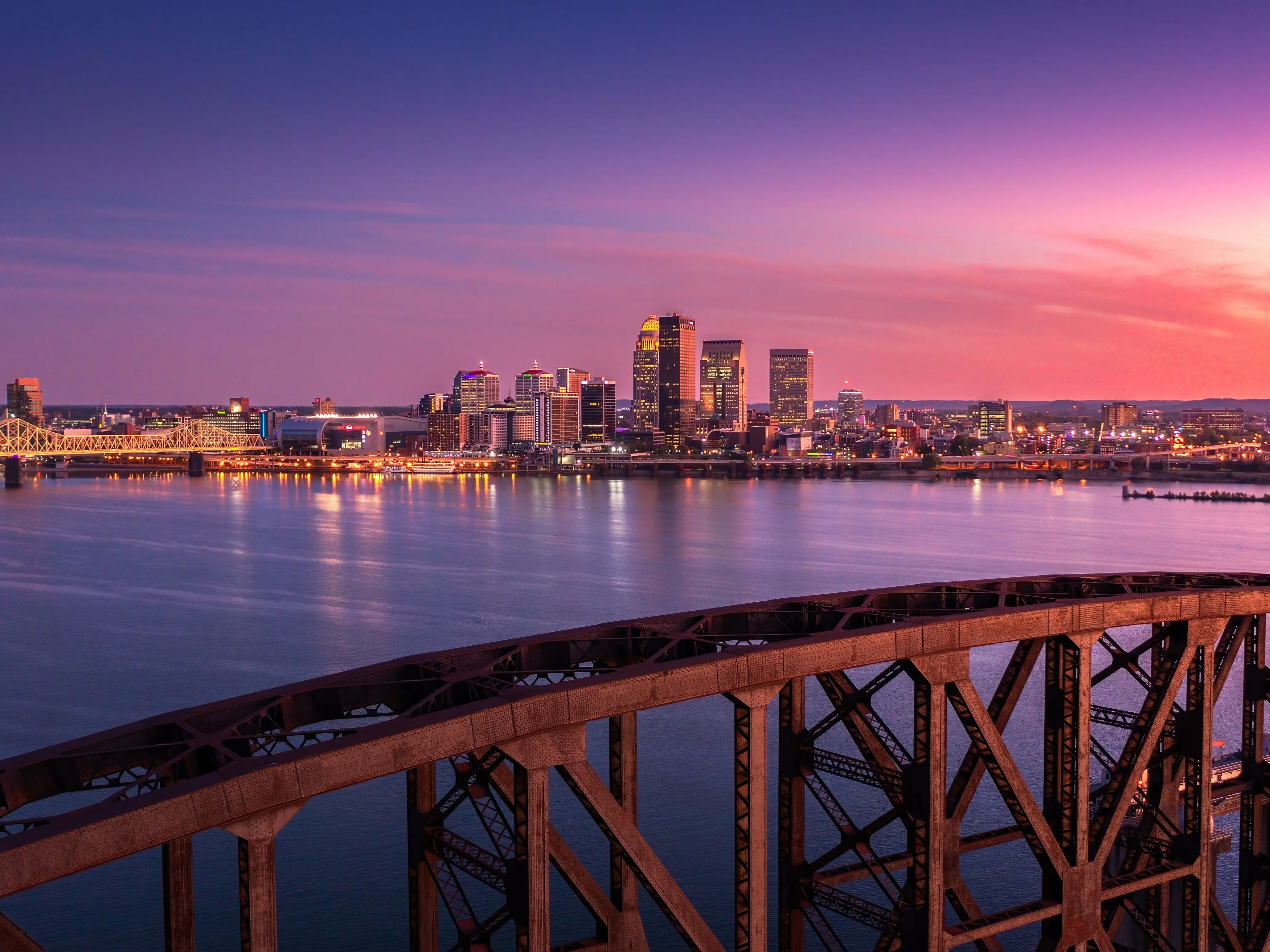 A bridge in front of the skyline of Louisville, Kentucky, at sunset.