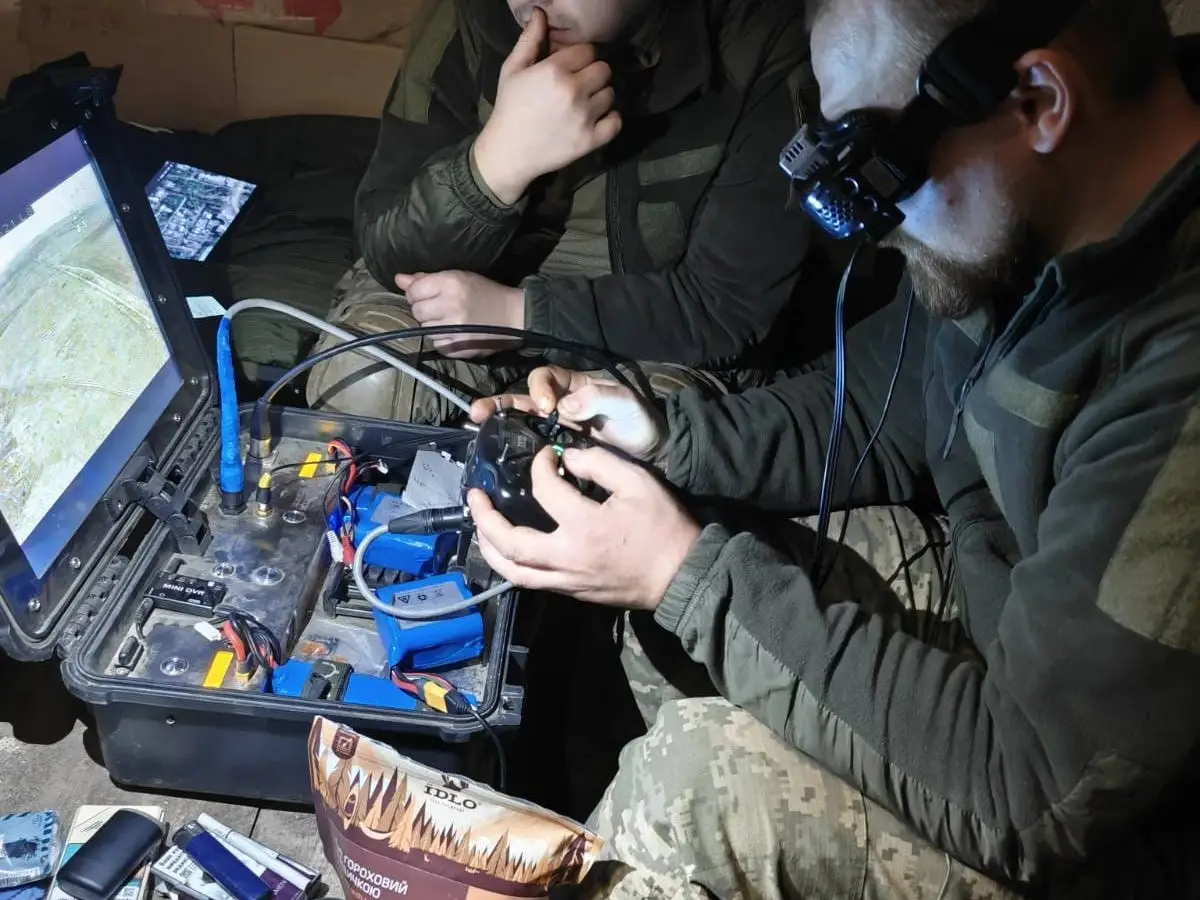 Two Ukrainian drone operators watch as a pilot flies inside a shelter.